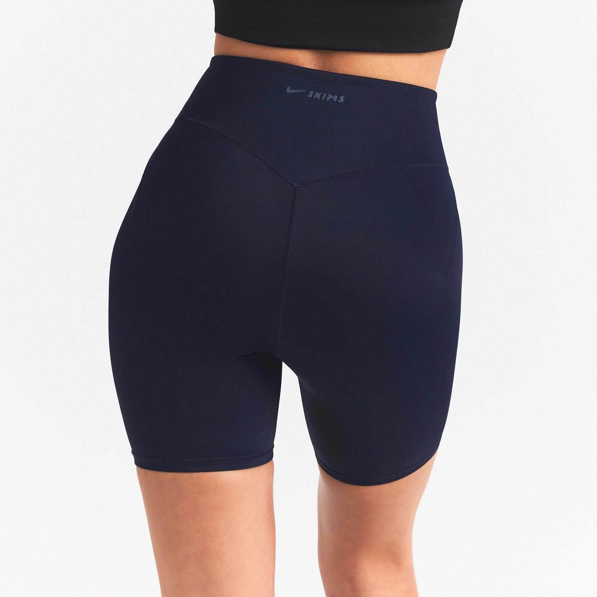 NikeSKIMS SHINE BONDED WAIST 5" BIKER SHORT | NAVY ON A MODEL SIDE VIEW @ | FOCUS: 0.0, 1.0, 0.9