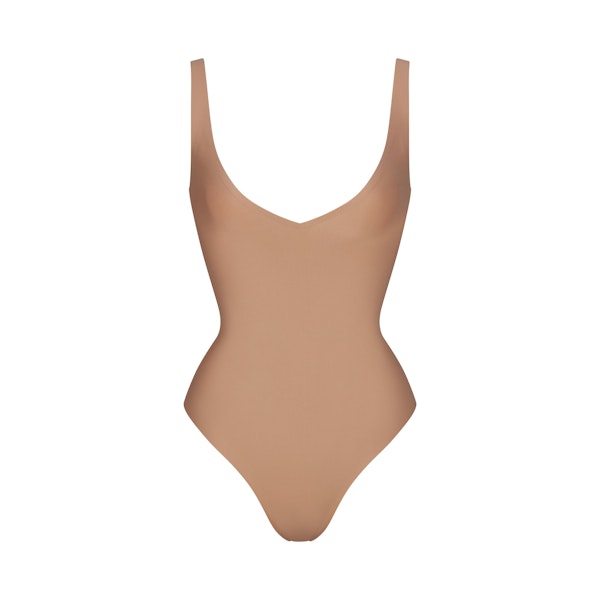 SKIMS BODY UNLINED PLUNGE THONG BODYSUIT | SIENNA (SHAPEWEAR BODYSUITS, SHAPEWEAR) LAYS FLAT ON A WHITE BACKGROUND | FLT