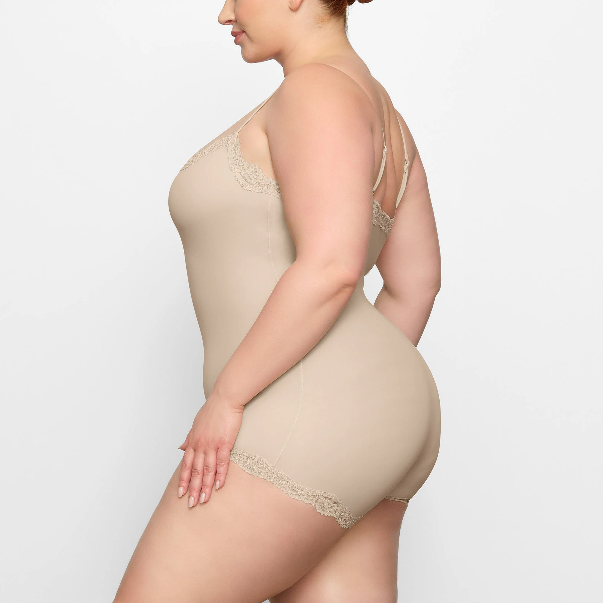 FITS EVERYBODY LACE ONESIE WORN BY A MODEL IN SIDE VIEW