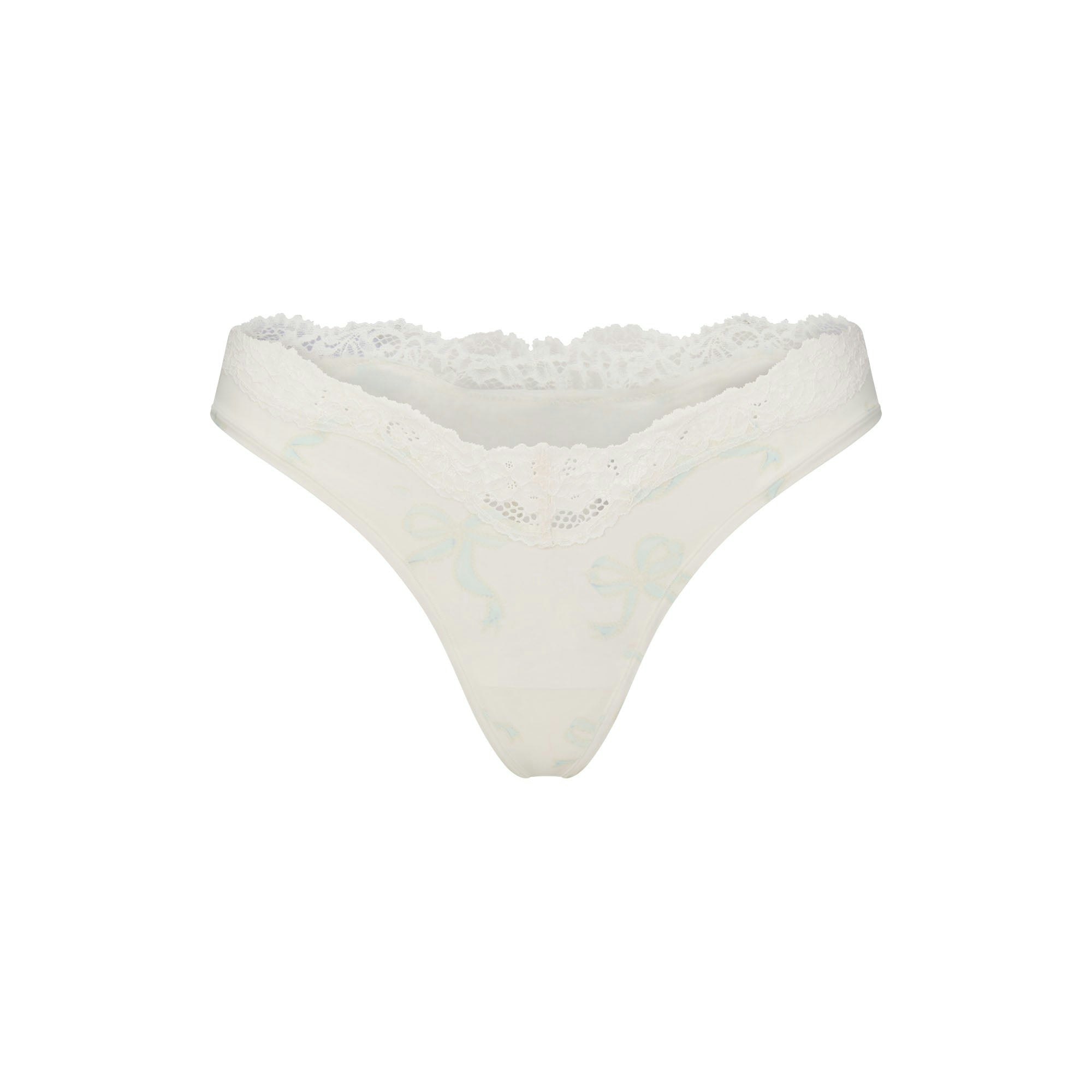 FITS EVERYBODY LACE DIPPED THONG 5-PACK | IVORY PEARL BOW MULTI LAYS FLAT ON A WHITE BACKGROUND
