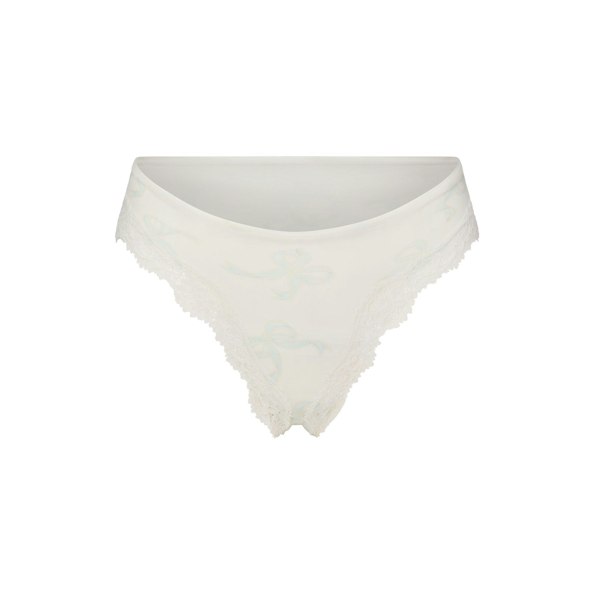FITS EVERYBODY LACE CHEEKY TANGA 5-PACK | IVORY PEARL BOW MULTI LAYS FLAT ON A WHITE BACKGROUND