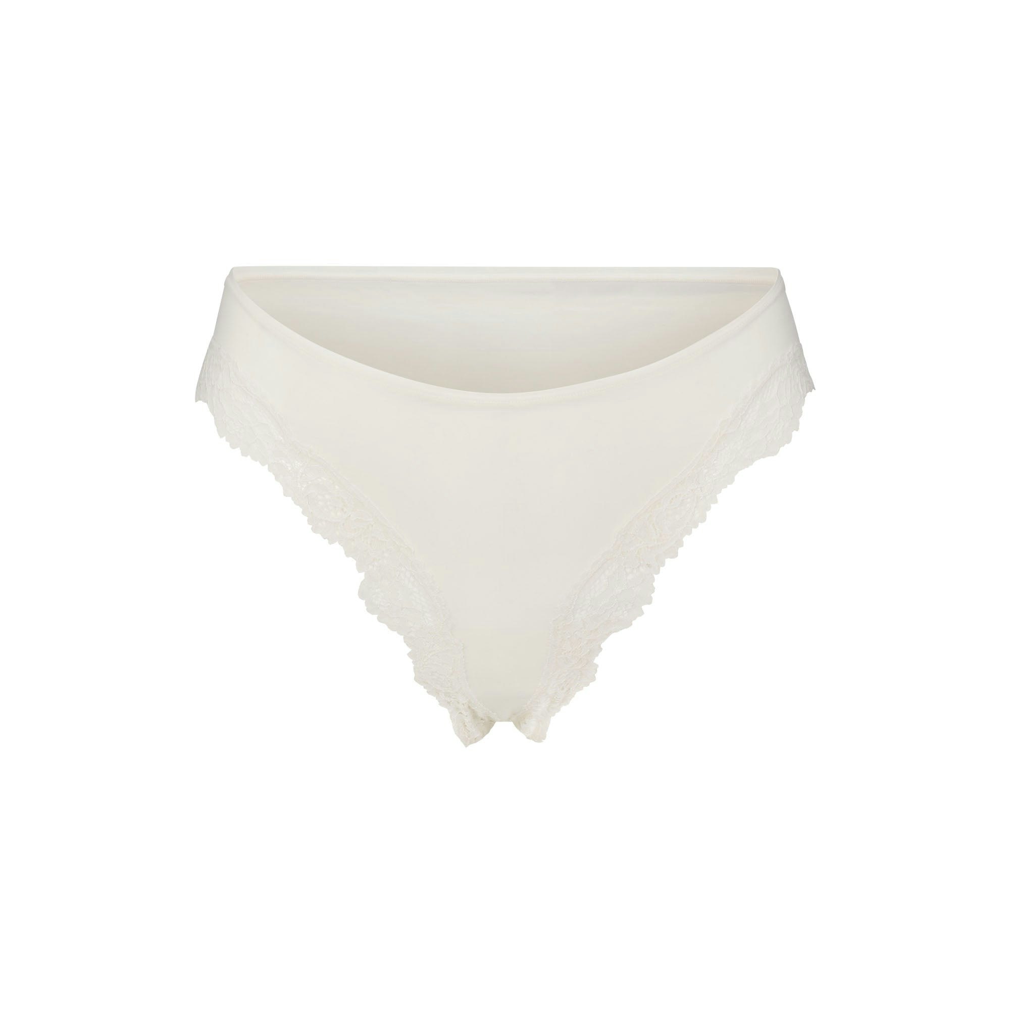 FITS EVERYBODY LACE CHEEKY TANGA 5-PACK | IVORY PEARL BOW MULTI LAYS FLAT ON A WHITE BACKGROUND