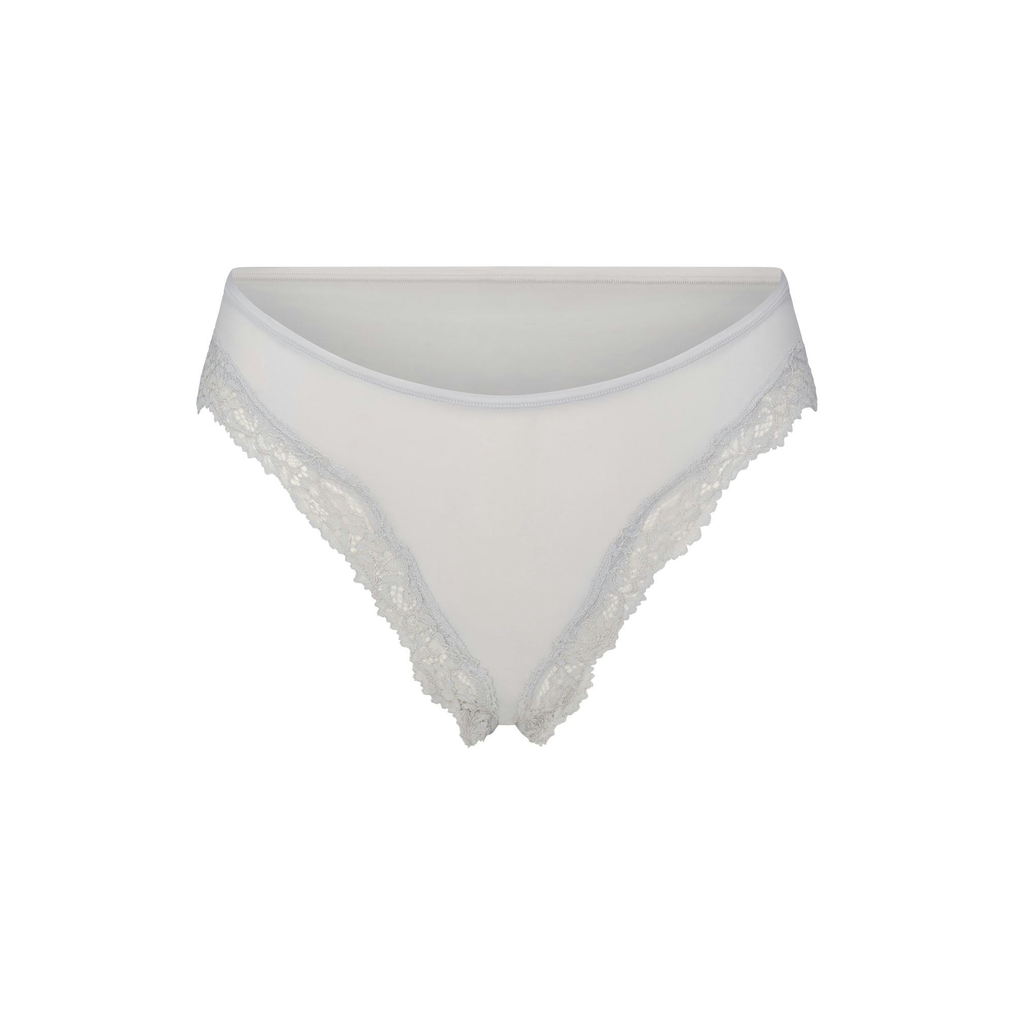 FITS EVERYBODY LACE CHEEKY TANGA 5-PACK | IVORY PEARL BOW MULTI LAYS FLAT ON A WHITE BACKGROUND