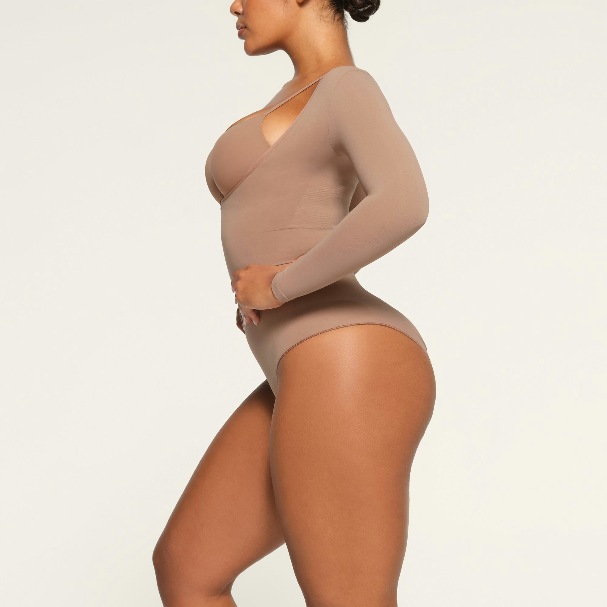 SEAMLESS SCULPT LONG SLEEVE OPEN BUST BRIEF BODYSUIT WORN BY A MODEL IN SIDE VIEW