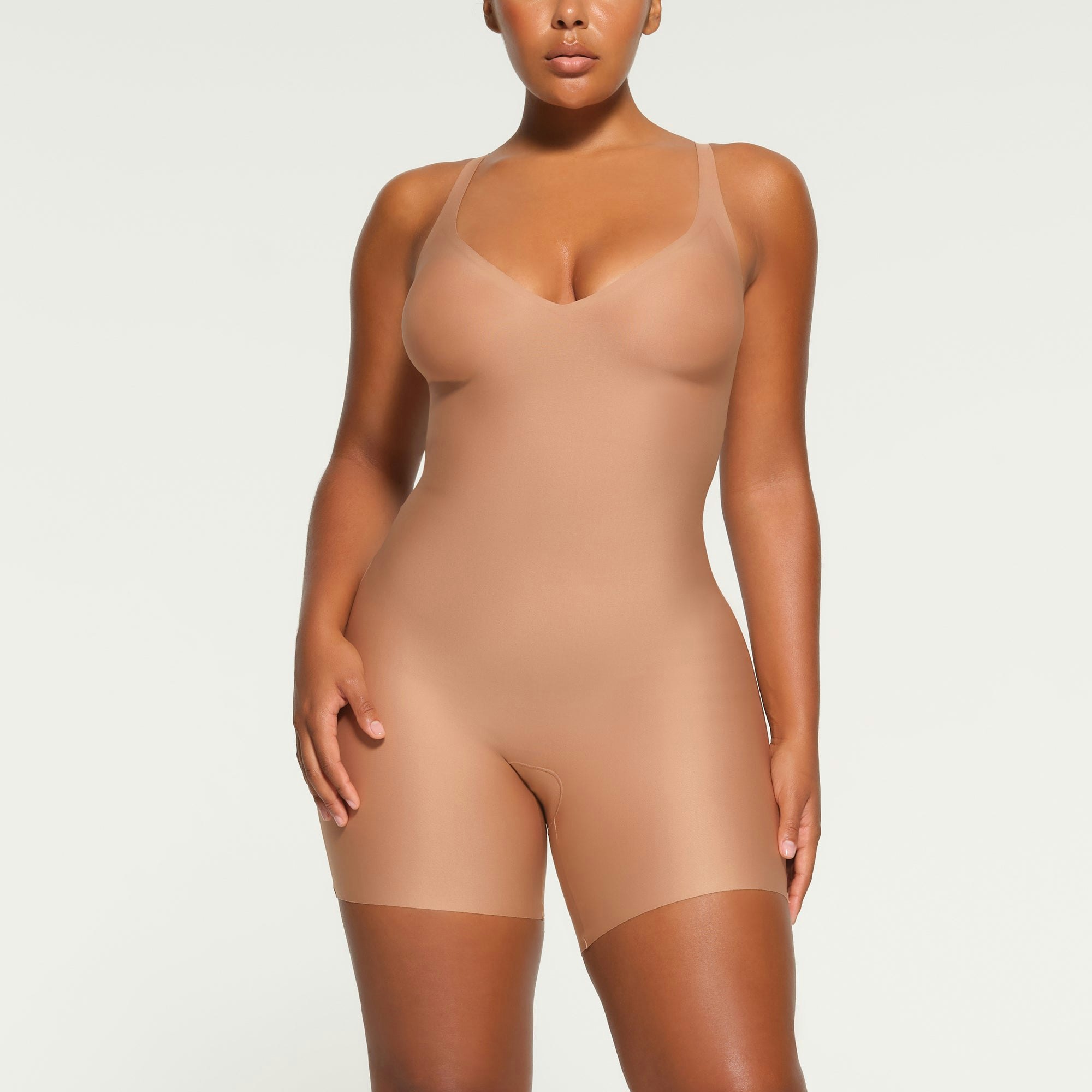 SKIMS BODY UNLINED PLUNGE MID-THIGH BODYSUIT WORN BY A MODEL IN FRONT VIEW