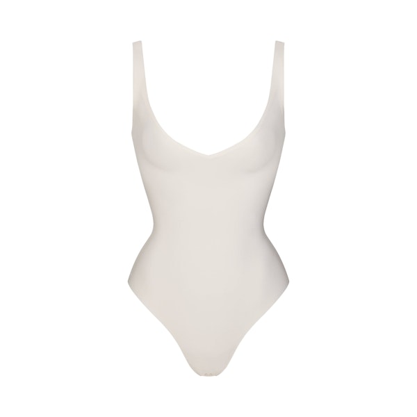 SKIMS BODY UNLINED PLUNGE THONG BODYSUIT | IVORY FLAT ON A WHITE BACKGROUND | FLT