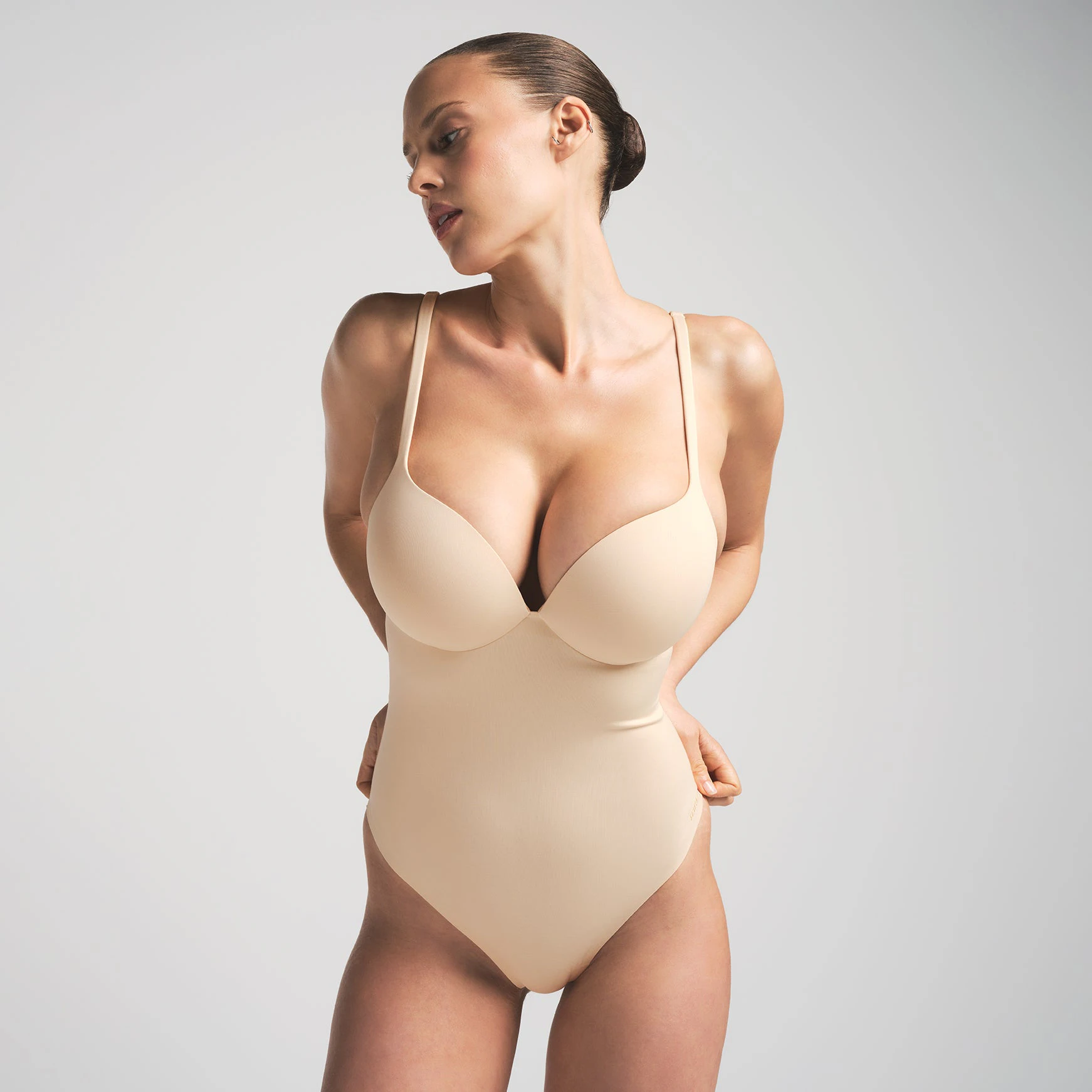 SKIMS ULTIMATE BODY PUSH-UP THONG BODYSUIT | SAND ON A MODEL FRONT VIEW