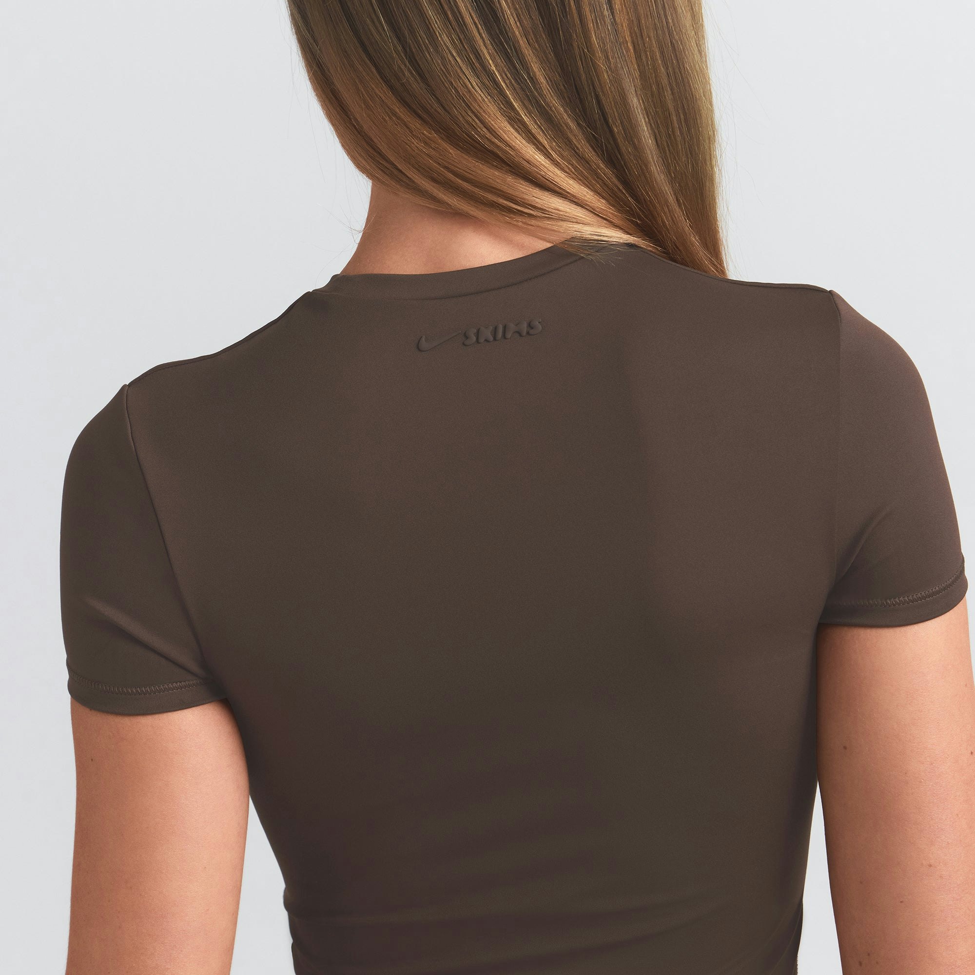 NikeSKIMS MATTE PADDED BABY TEE | DARK SEPIA ON A MODEL BACK VIEW @ | FOCUS: 0.0, 1.0, 0.9