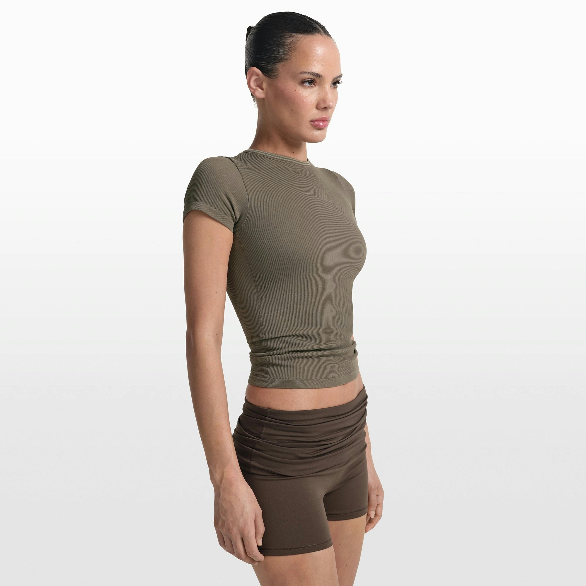 NikeSKIMS RIBBED SEAMLESS BABY TEE | DUSTY OAKMOSS/DUNE ON A MODEL FRONT VIEW @ | FOCUS: 0.0, 1.0, 0.9