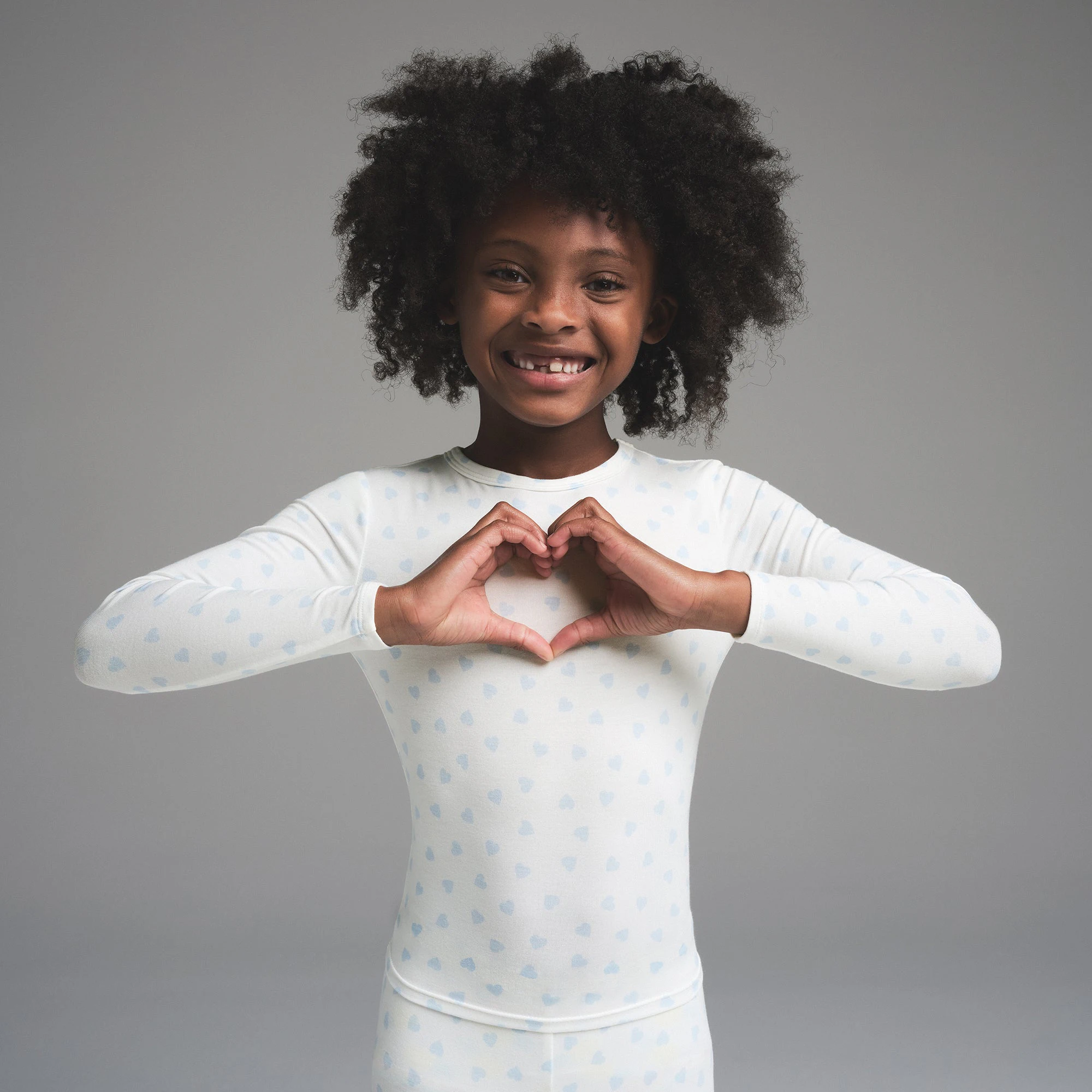 SKIMS SLEEP KIDS SLEEP SET | MARBLE CLOUD HEART PRINT ON A MODEL SIDE VIEW | FOCUS: 0.0, 1.0, 0.9