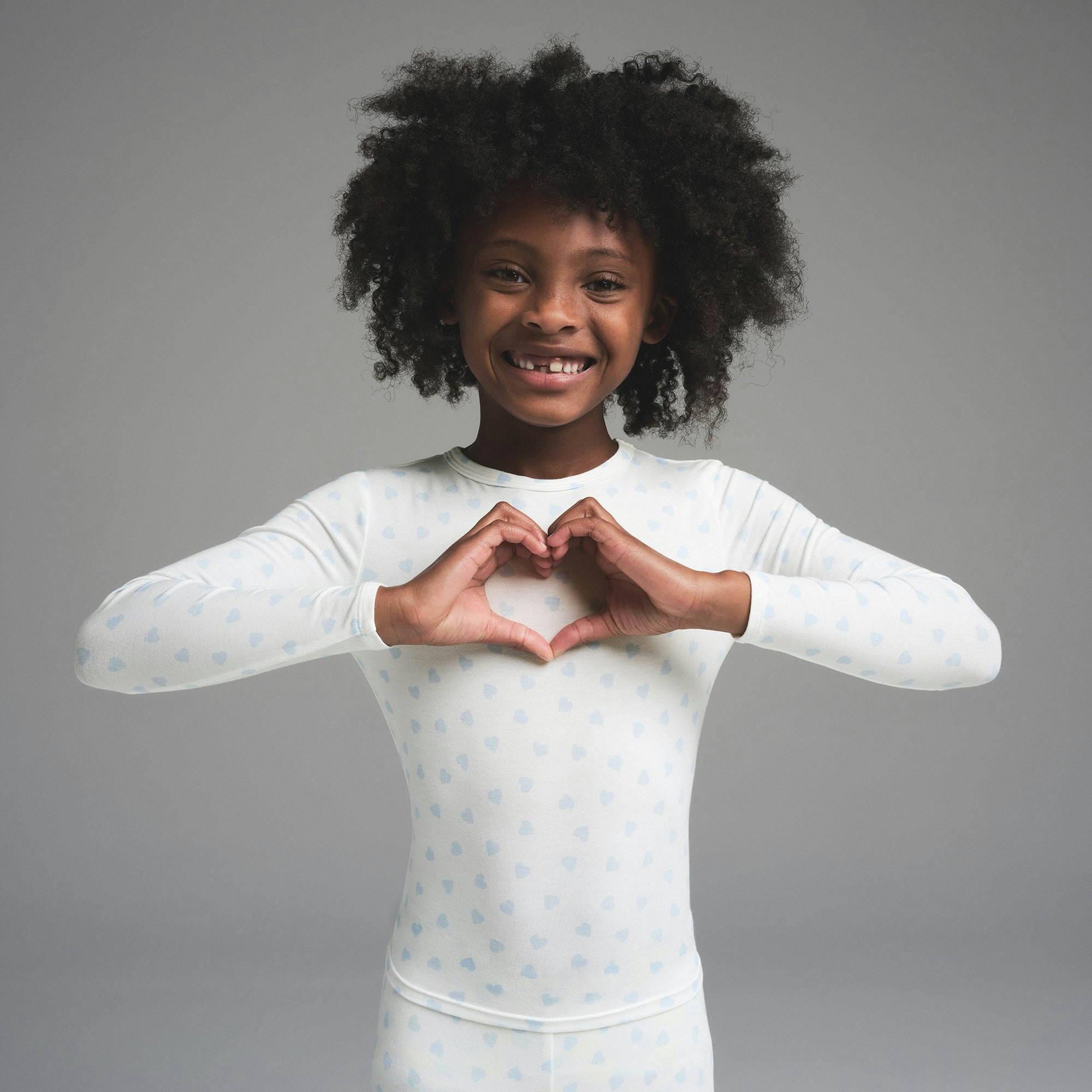 SKIMS SLEEP KIDS SLEEP SET | MARBLE CLOUD HEART PRINT ON A MODEL SIDE VIEW | FOCUS: 0.0, 1.0, 0.9