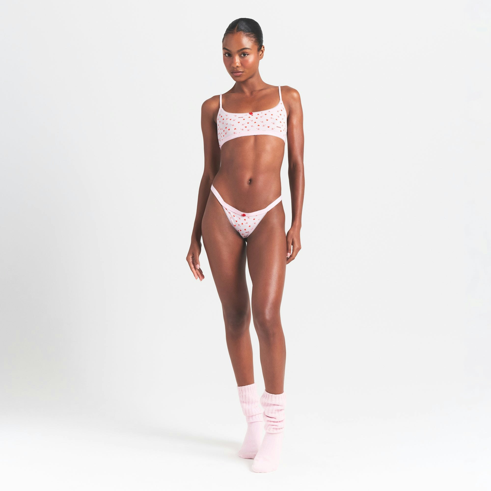 LIGHTWEIGHT COTTON LOGO PICOT THONG | BABY PINK ARROWED HEARTS ON A MODEL FRONT VIEW @ | FOCUS: 0.0, 1.0, 0.9