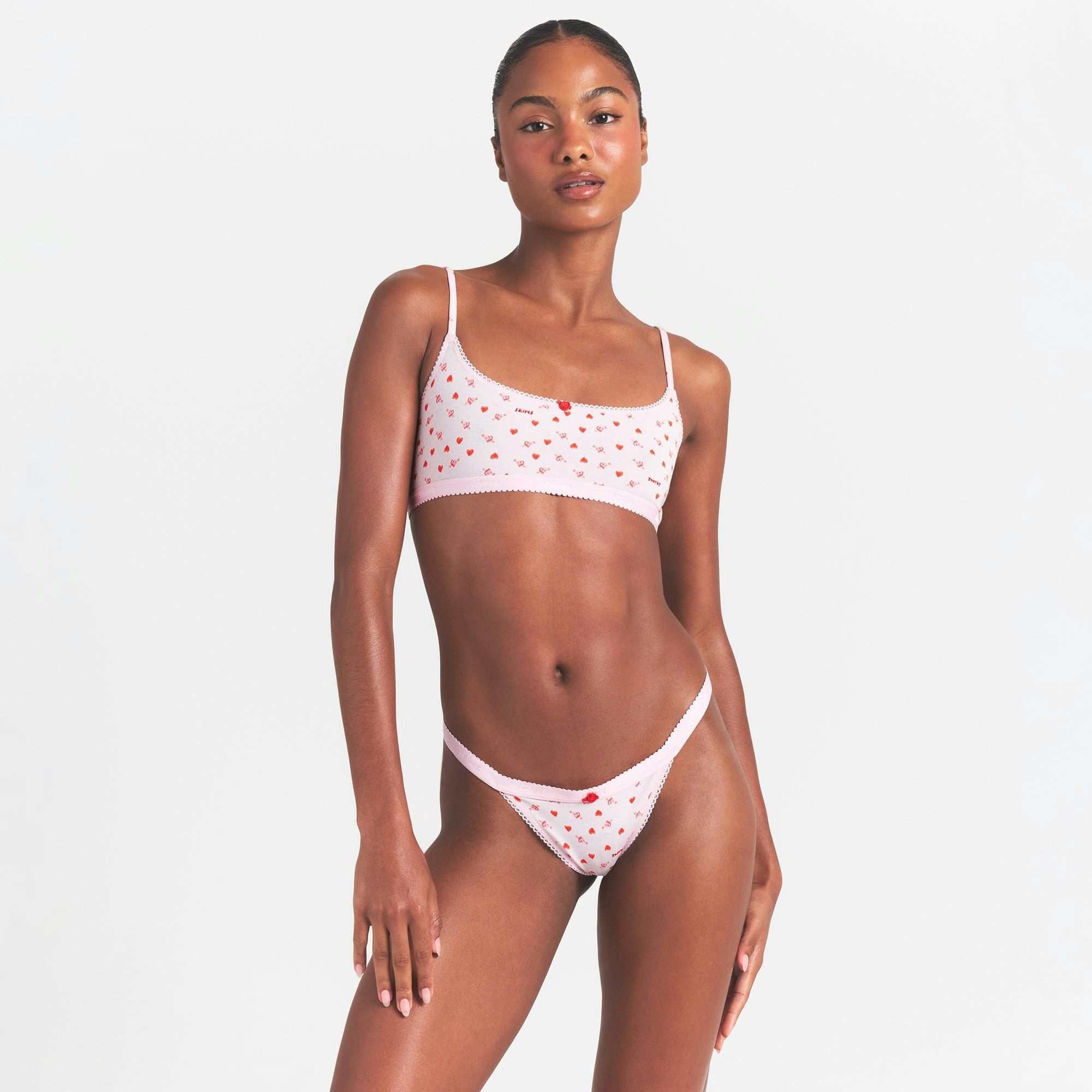 LIGHTWEIGHT COTTON LOGO PICOT THONG | BABY PINK ARROWED HEARTS ON A MODEL SIDE VIEW @ | FOCUS: 0.0, 1.0, 0.9