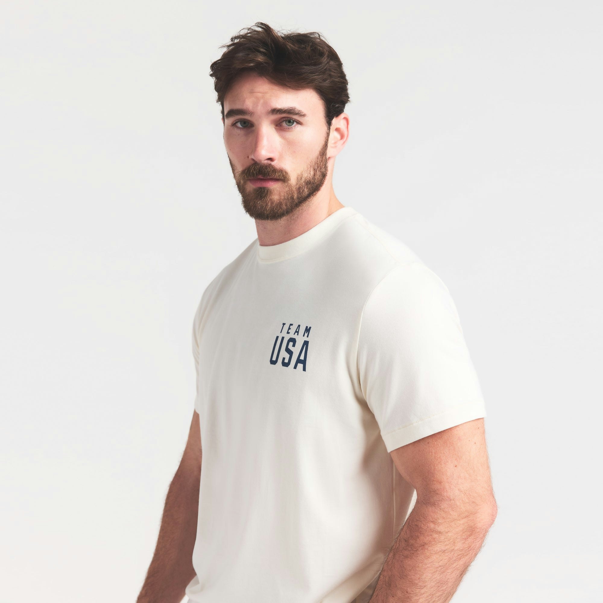 SKIMS FOR TEAM USA JERSEY SLEEP MENS OLYMPIC T-SHIRT | ECRU ON A MODEL SIDE VIEW @ | FOCUS: 0.0, 1.0, 0.9