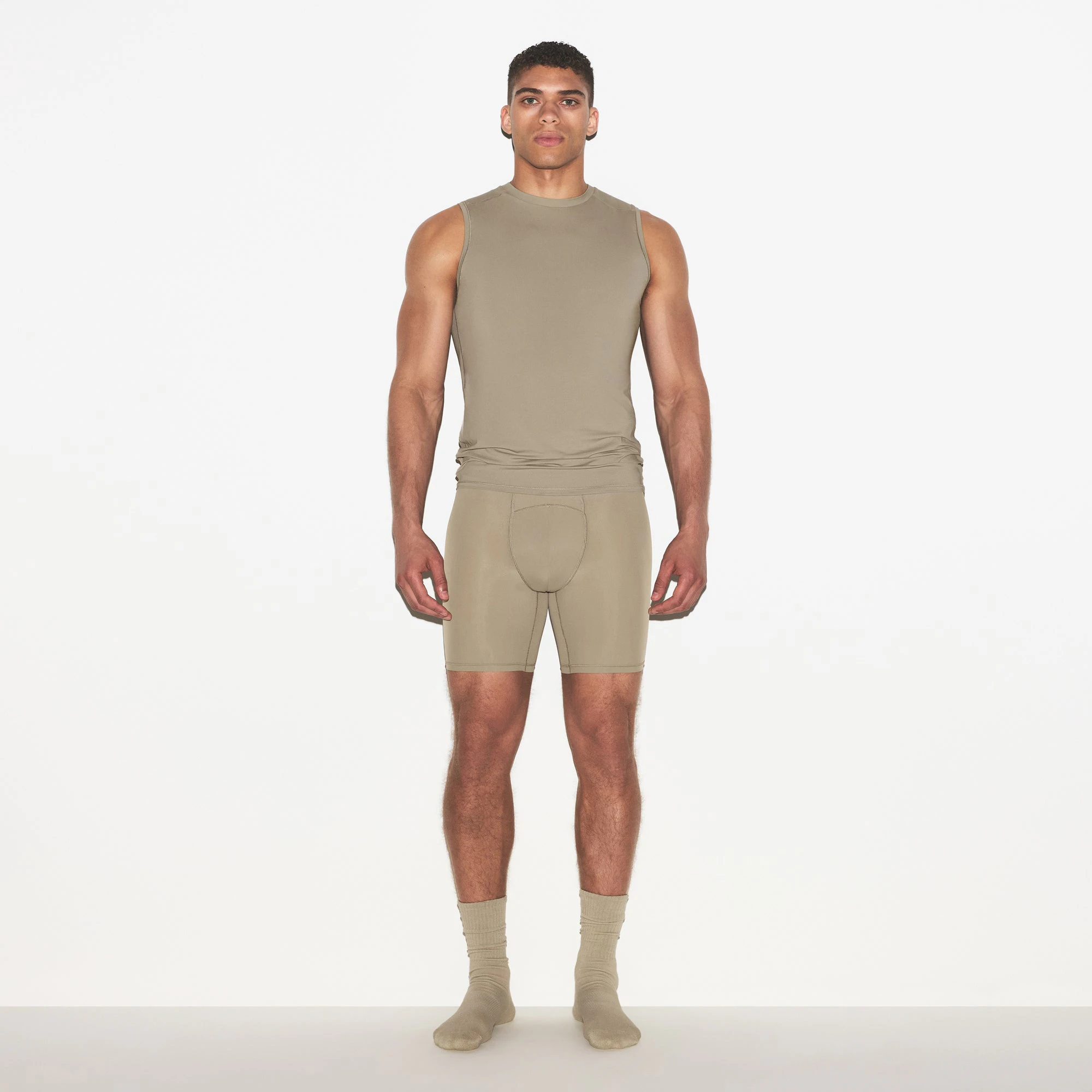 SKIMS SPORT MENS MUSCLE TANK | DUNE ON A MODEL SIDE VIEW @ | FOCUS: 0.0, 1.0, 0.9