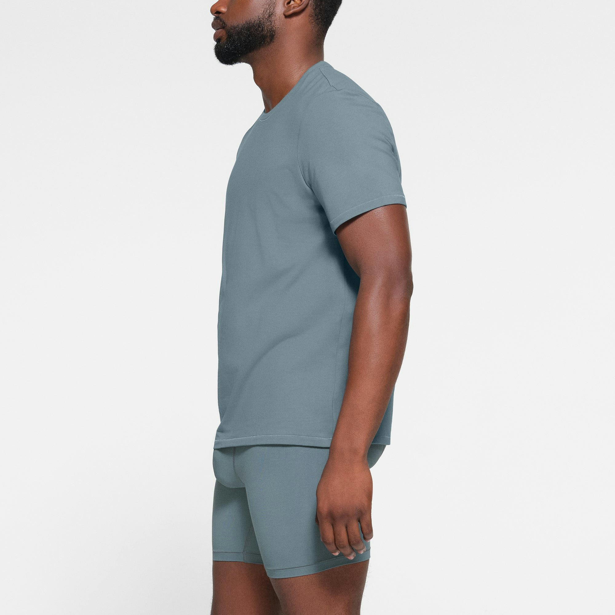 SKIMS COTTON MENS T-SHIRT WORN BY A MODEL IN SIDE VIEW