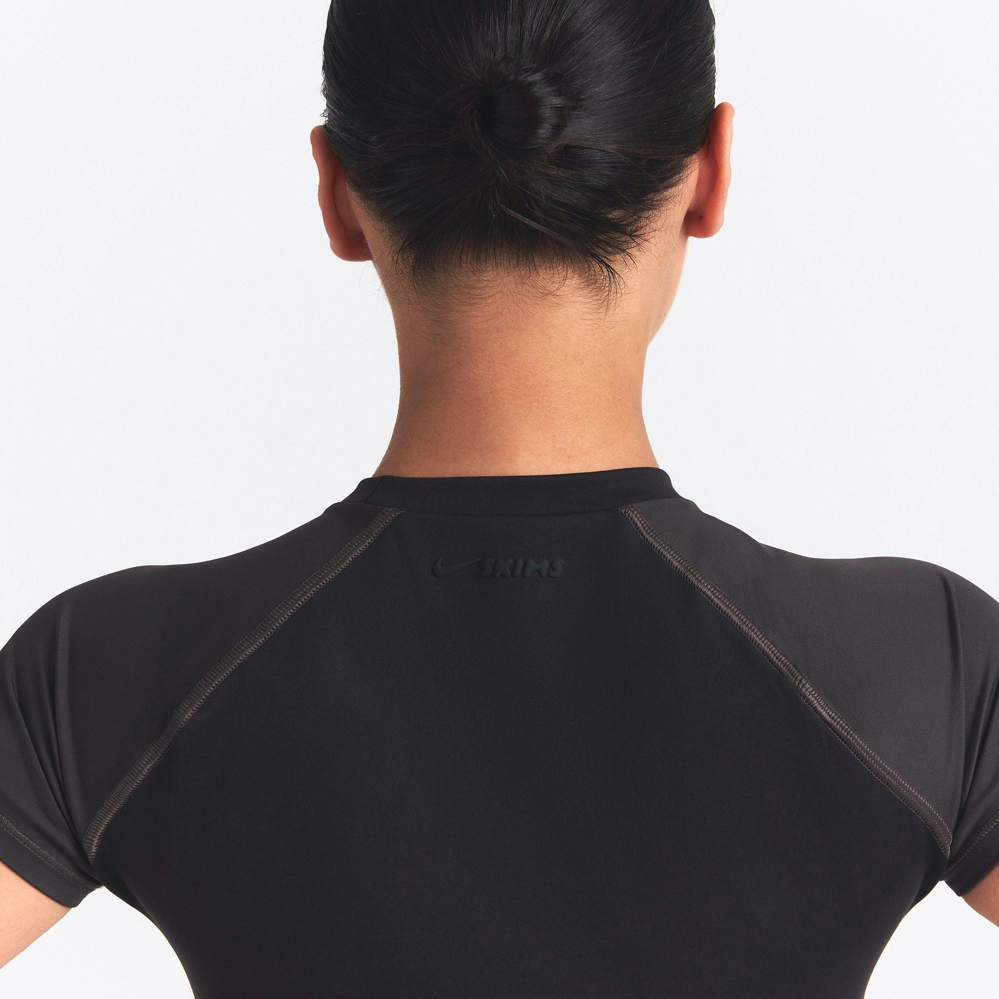 NikeSKIMS MATTE AND SHINE CREWNECK CROP SHORT SLEEVE | OBSIDIAN/IGNEOUS ON A MODEL SIDE VIEW @ | FOCUS: 0.0, 1.0, 0.9