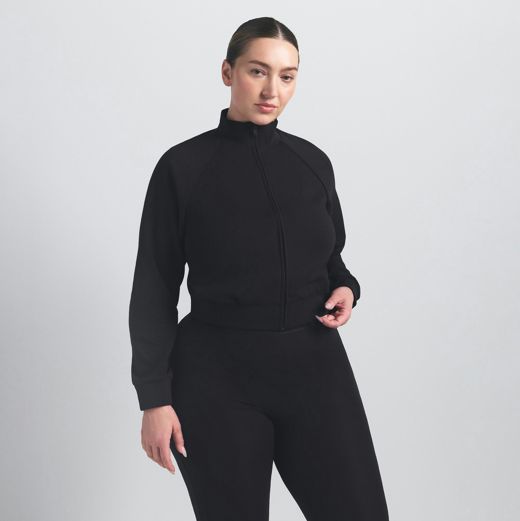 NikeSKIMS MATTE TRICOT TRACK JACKET | OBSIDIAN ON A MODEL SIDE VIEW @ | FOCUS: 0.9, 0.1, 0.7