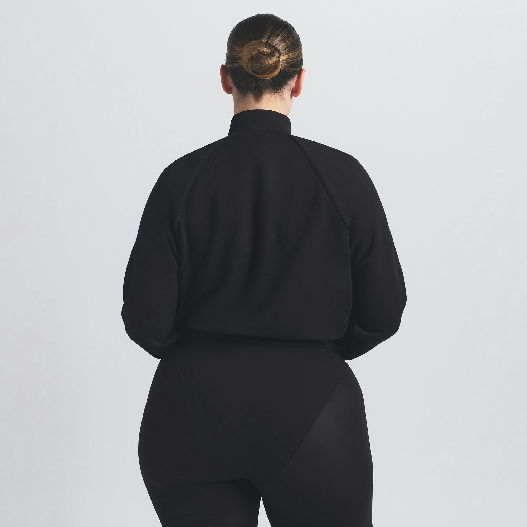 NikeSKIMS MATTE TRICOT TRACK JACKET | OBSIDIAN ON A MODEL SIDE VIEW @ | FOCUS: 0.9, 0.1, 0.7