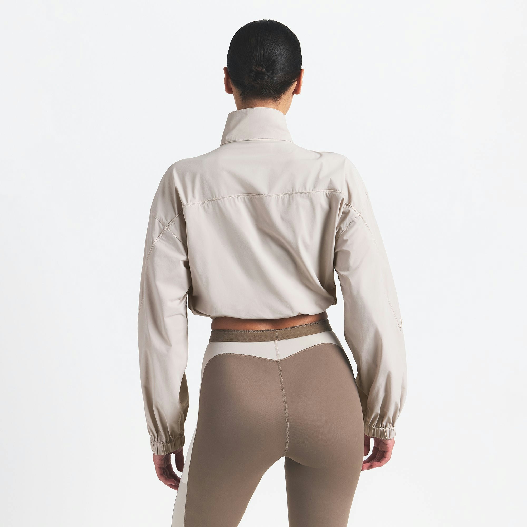 NikeSKIMS WOVEN NYLON CROP JACKET | STONE ON A MODEL BACK VIEW @ | FOCUS: 0.0, 1.0, 0.9