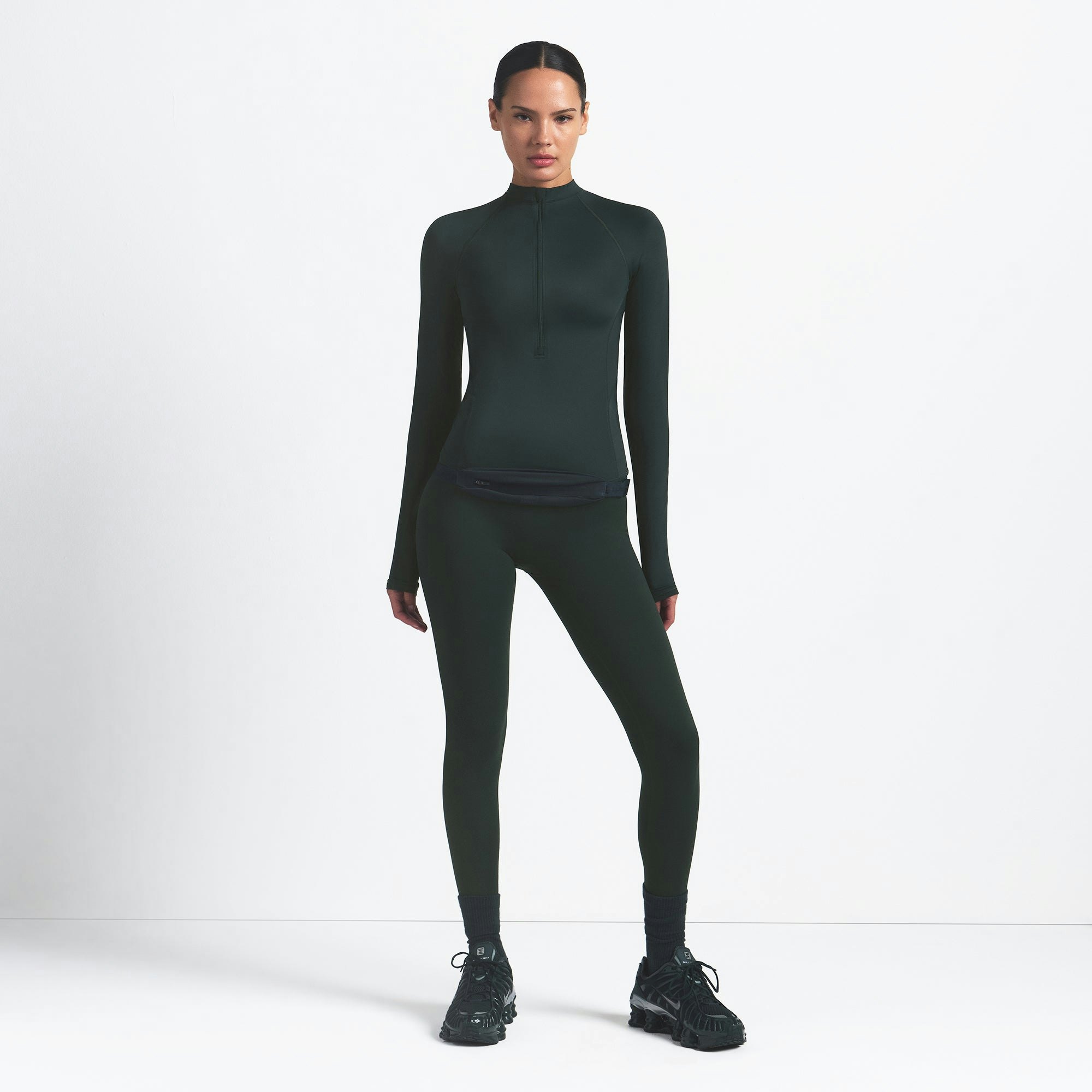 NikeSKIMS SHINE LONG SLEEVE HALF ZIP | DARK TEAL ON A MODEL SIDE VIEW @ | FOCUS: 0.0, 1.0, 0.9