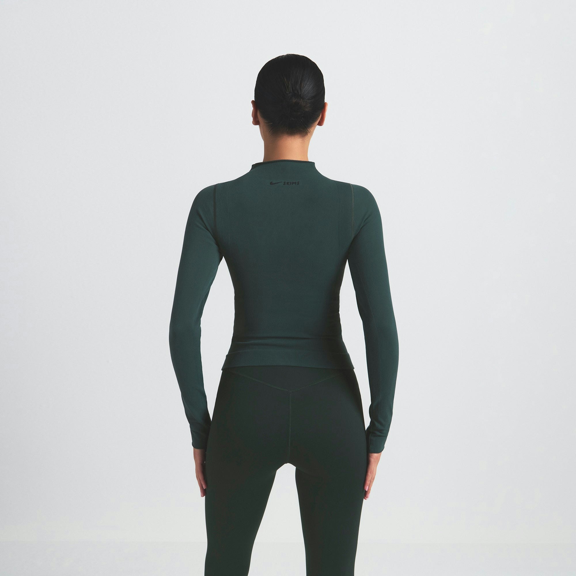 NikeSKIMS VINTAGE SEAMLESS FULL ZIP JACKET | DARK TEAL ON A MODEL SIDE VIEW @ | FOCUS: 0.0, 1.0, 0.9