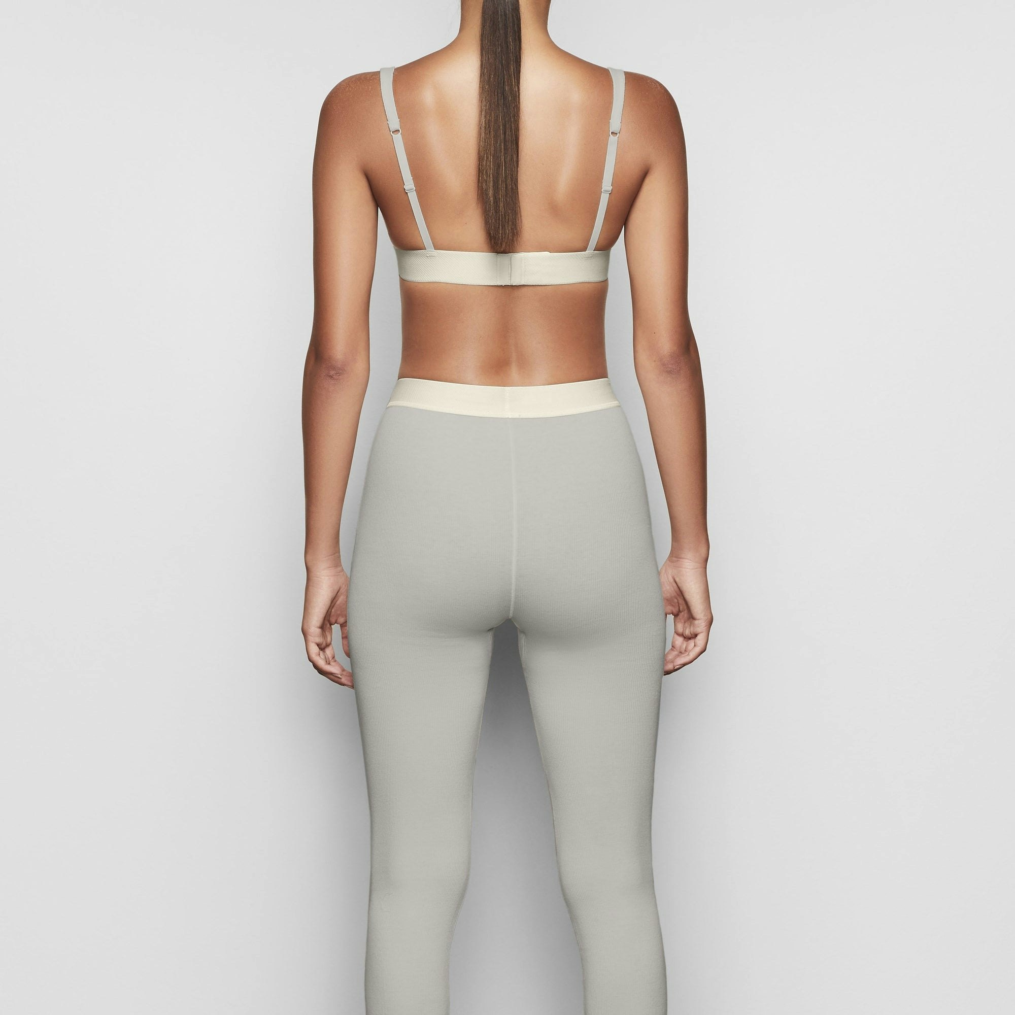 A MODEL STANDS WITH HER BACK TO THE CAMERA SHOWING THE COTTON RIB LEGGING | MINERAL