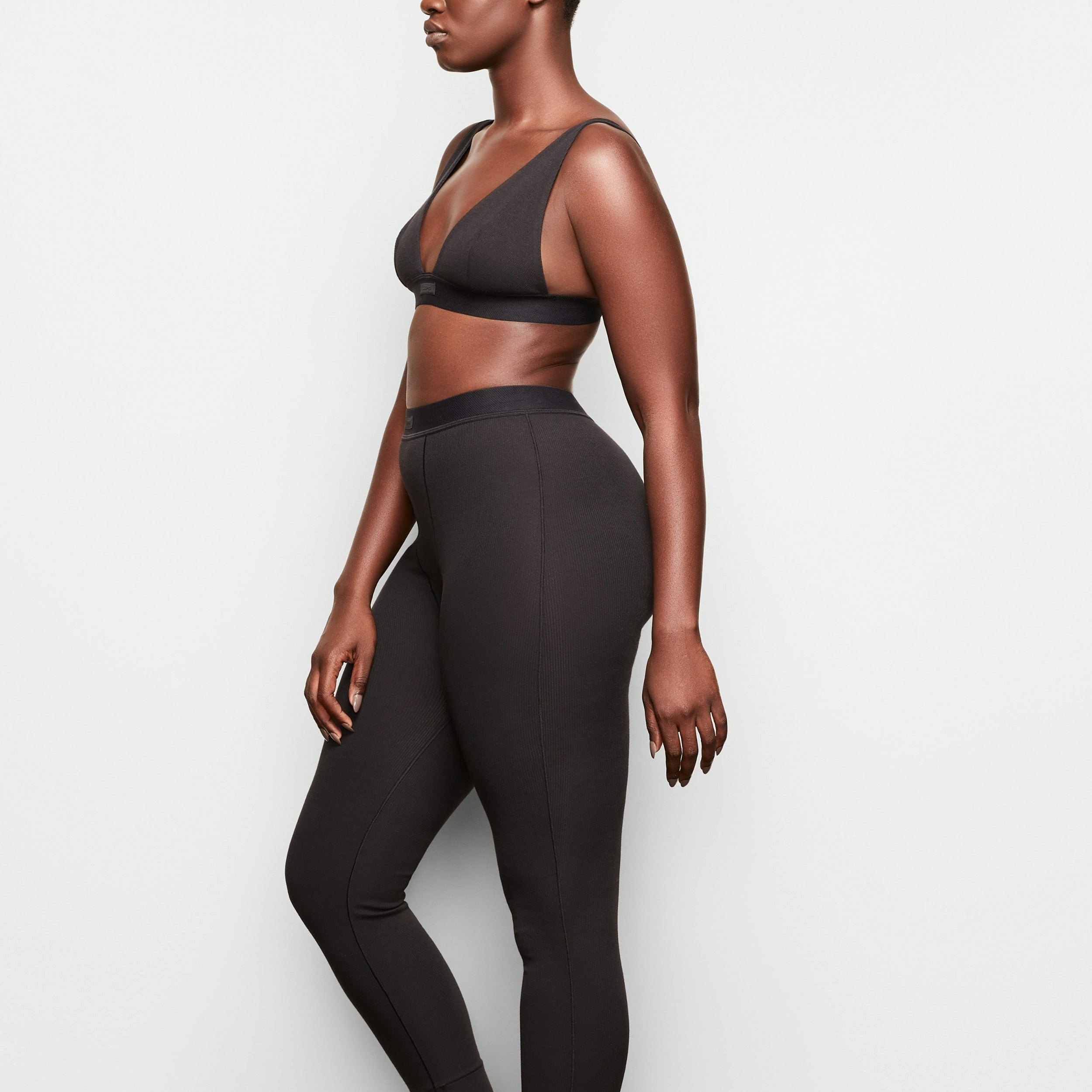 A MODEL STANDS WITH HER BACK TO THE CAMERA SHOWING THE COTTON RIB LEGGING | SOOT