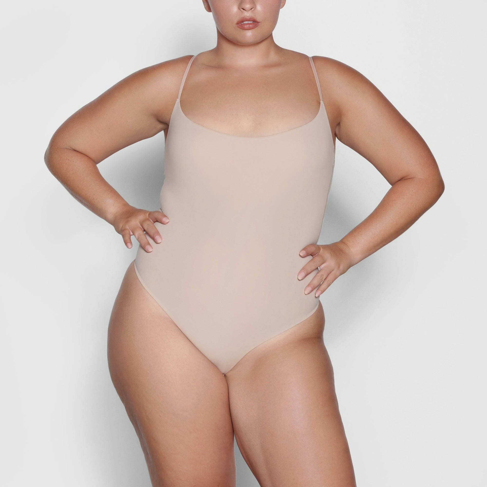 A MODEL STANDS FACING FORWARD WEARING THE SKIMS FITS EVERYBODY CAMI BODYSUIT IN MICA | SEE: XL