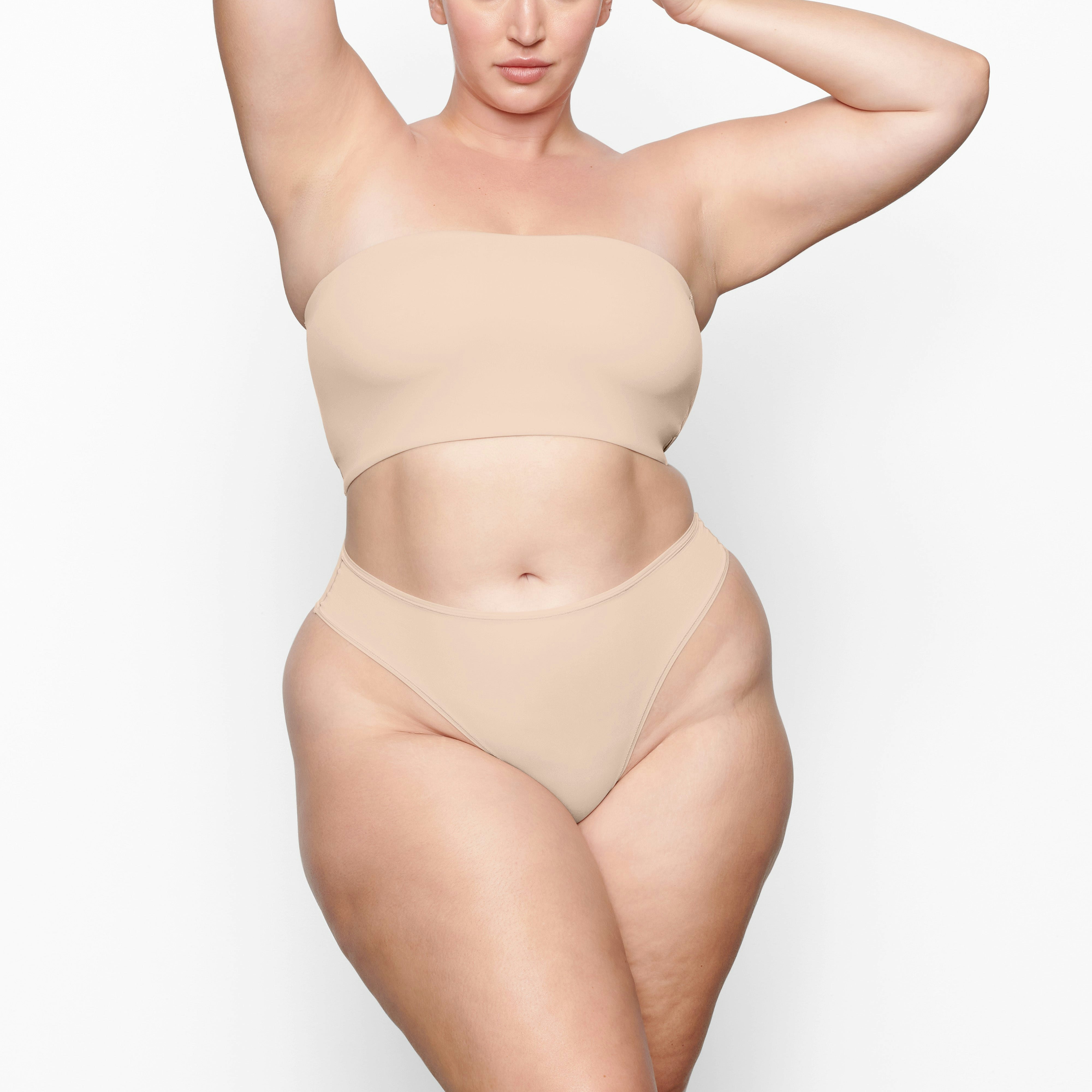 A MODEL STANDS FACING FORWARD WEARING THE SKIMS FITS EVERYBODY BANDEAU BRA IN MICA | SEE: 2X, 3X, 4X