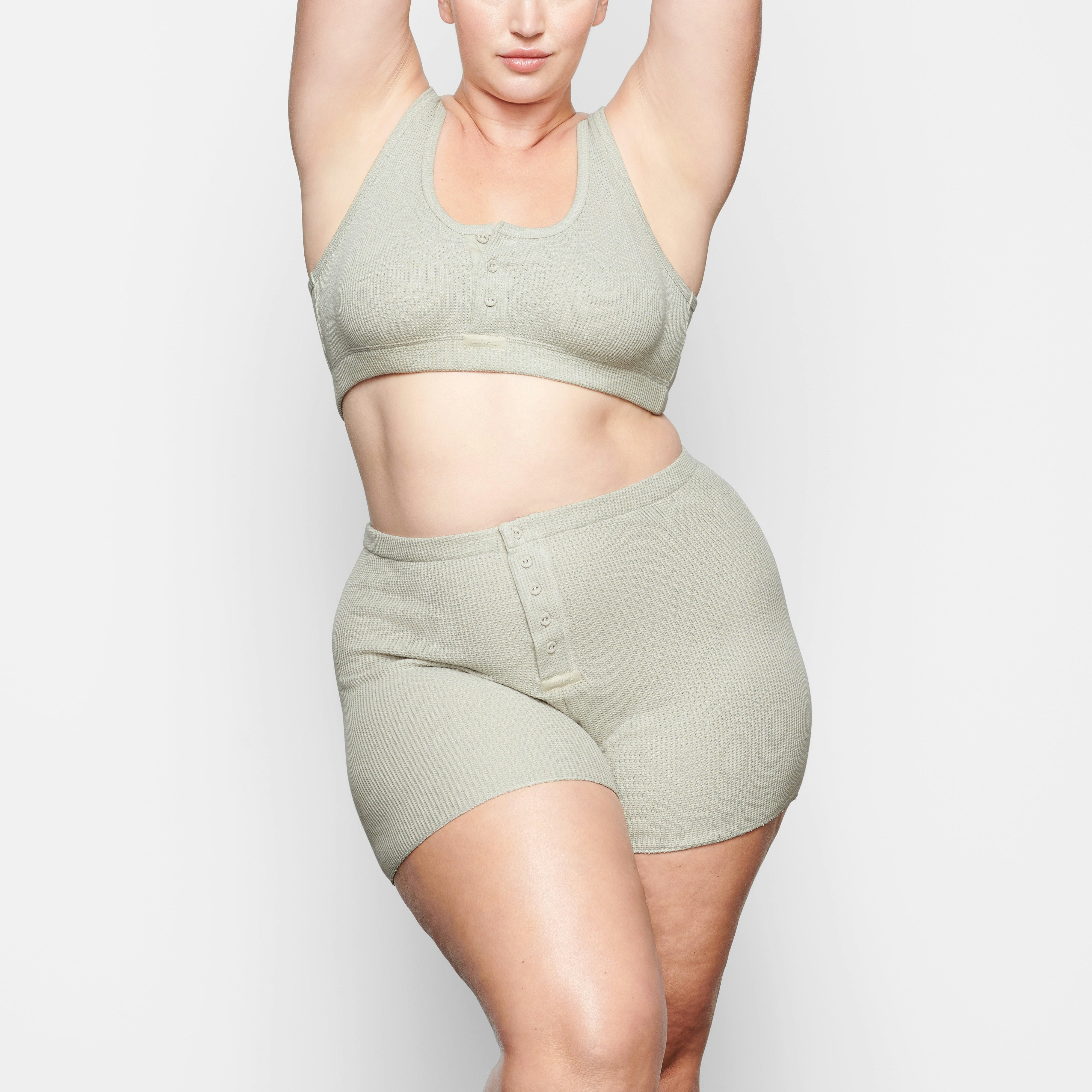 A MODEL STANDS FACING FORWARD WEARING THE SKIMS WAFFLE HENLEY BRA IN TALC | SEE: 2X, 3X, 4X