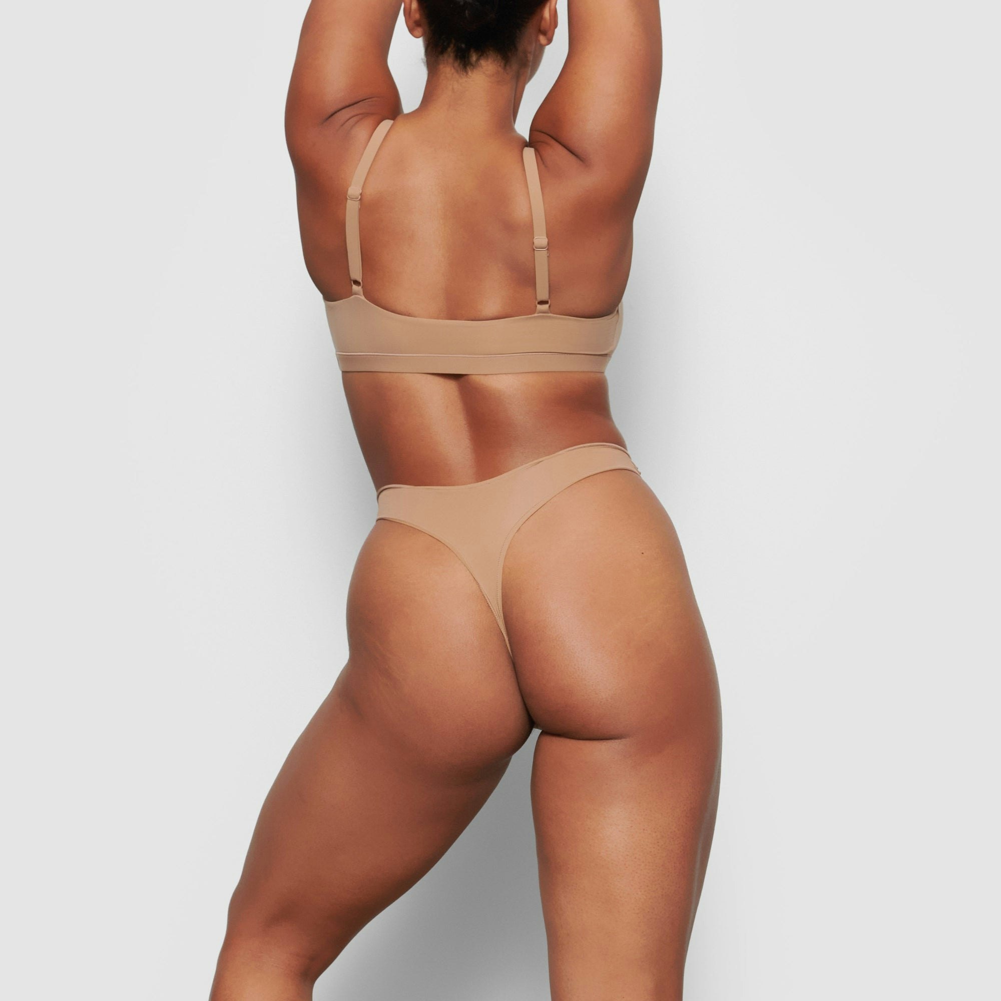A MODEL STANDS WITH HER BACK TO THE CAMERA SHOWING THE FITS EVERYBODY SCOOP NECK BRA | SIENNA