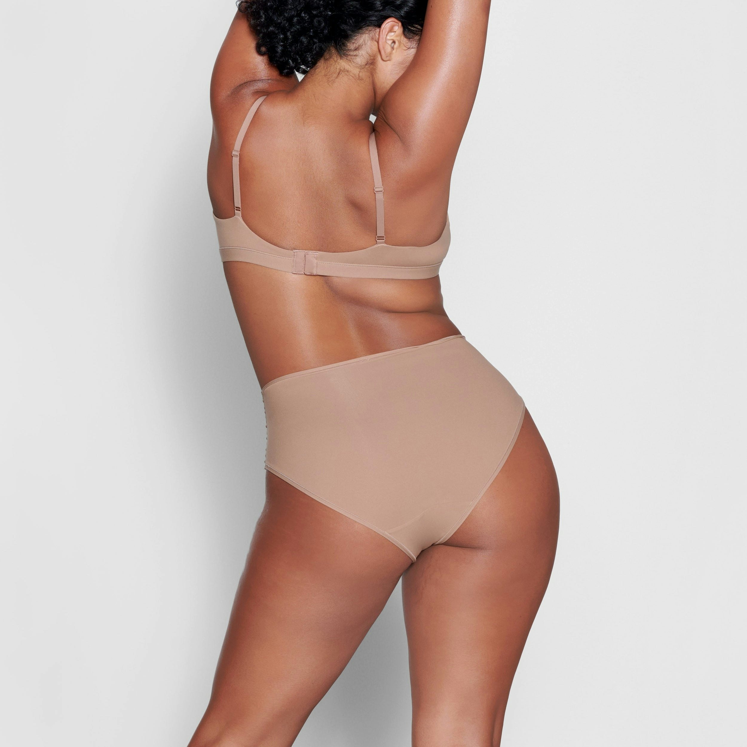 A MODEL STANDS WITH HER BACK TO THE CAMERA SHOWING THE FITS EVERYBODY CROSSOVER BRALETTE | SIENNA