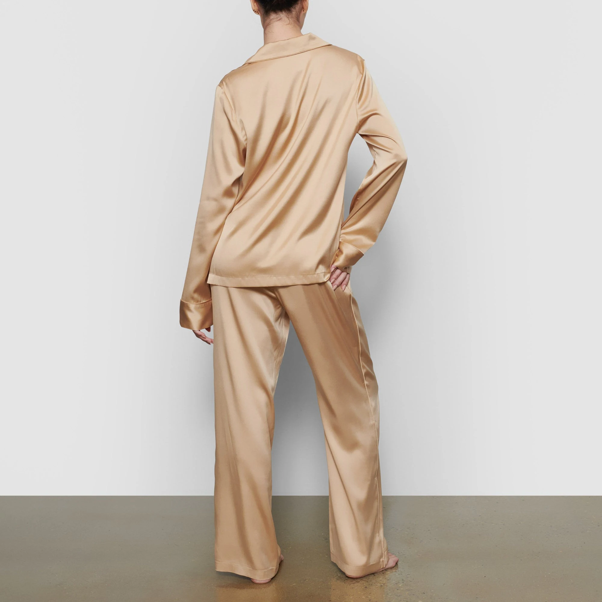 A MODEL STANDS WITH HER BACK TO THE CAMERA SHOWING THE SILK SLEEP PANT | HONEY
