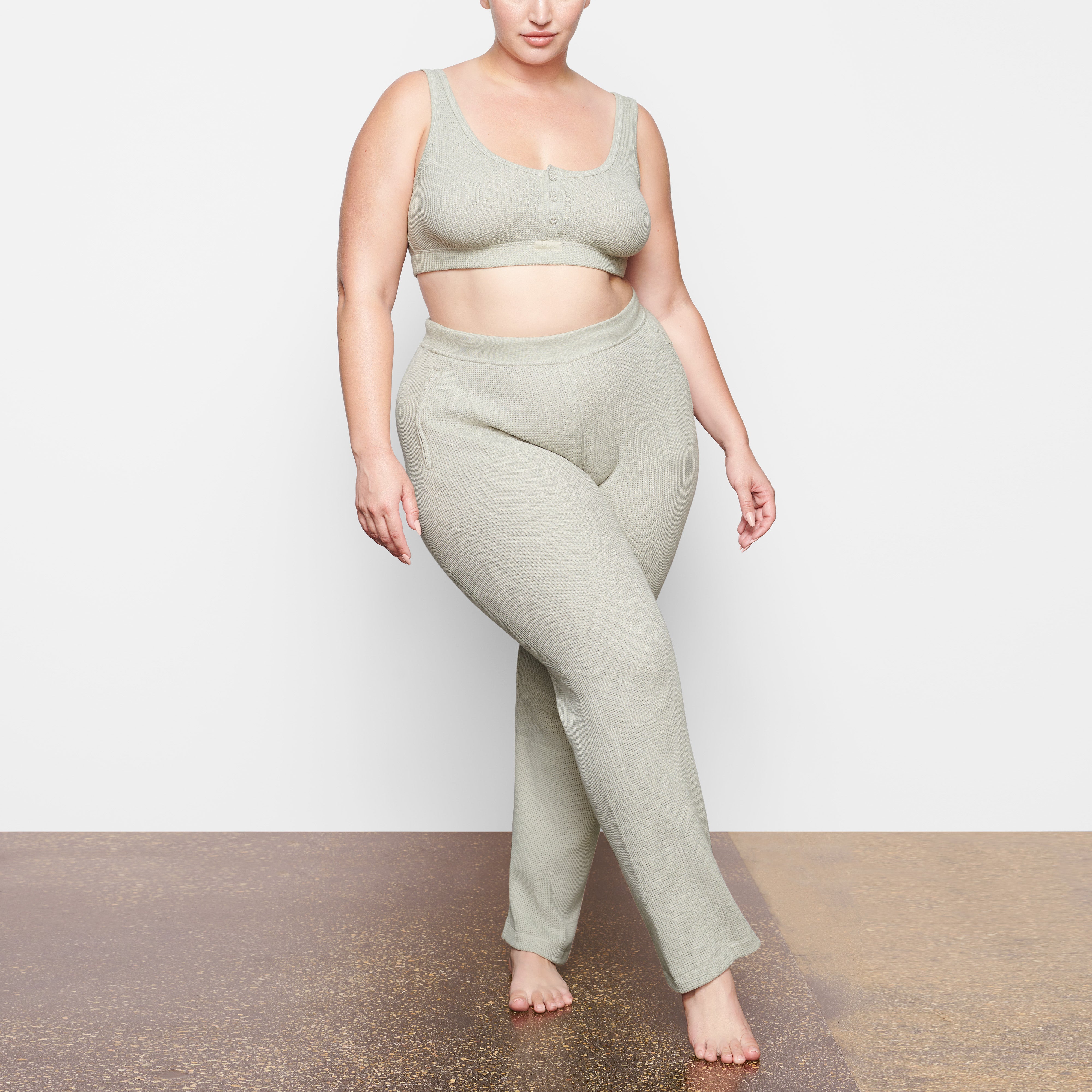 A MODEL STANDS FACING FORWARD WEARING THE SKIMS WAFFLE LOOSE PANT IN TALC | SEE: 2X, 3X, 4X