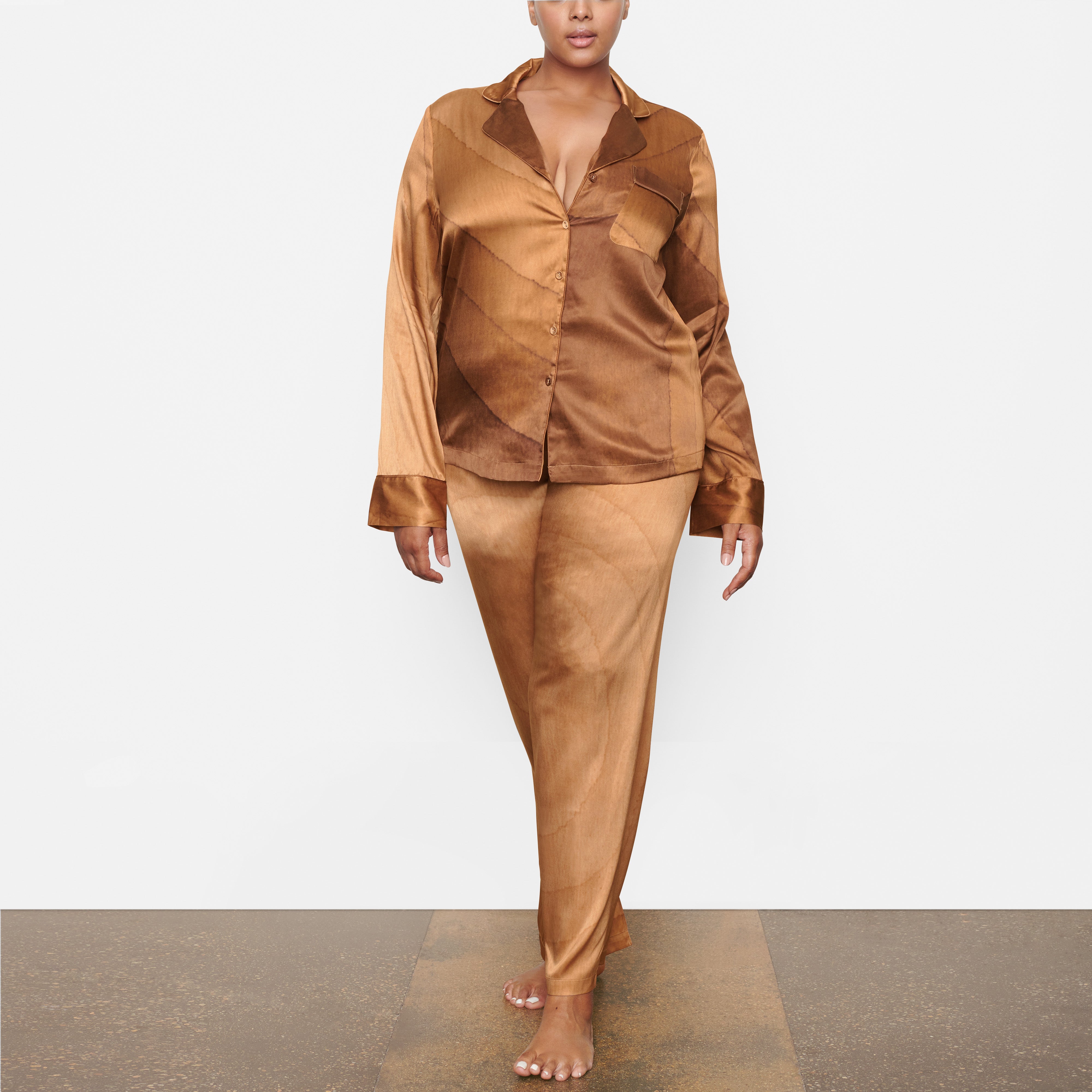 A MODEL STANDS FACING FORWARD WEARING THE SKIMS SILK BUTTON UP SHIRT IN OAK | SEE: 2X, 3X, 4X