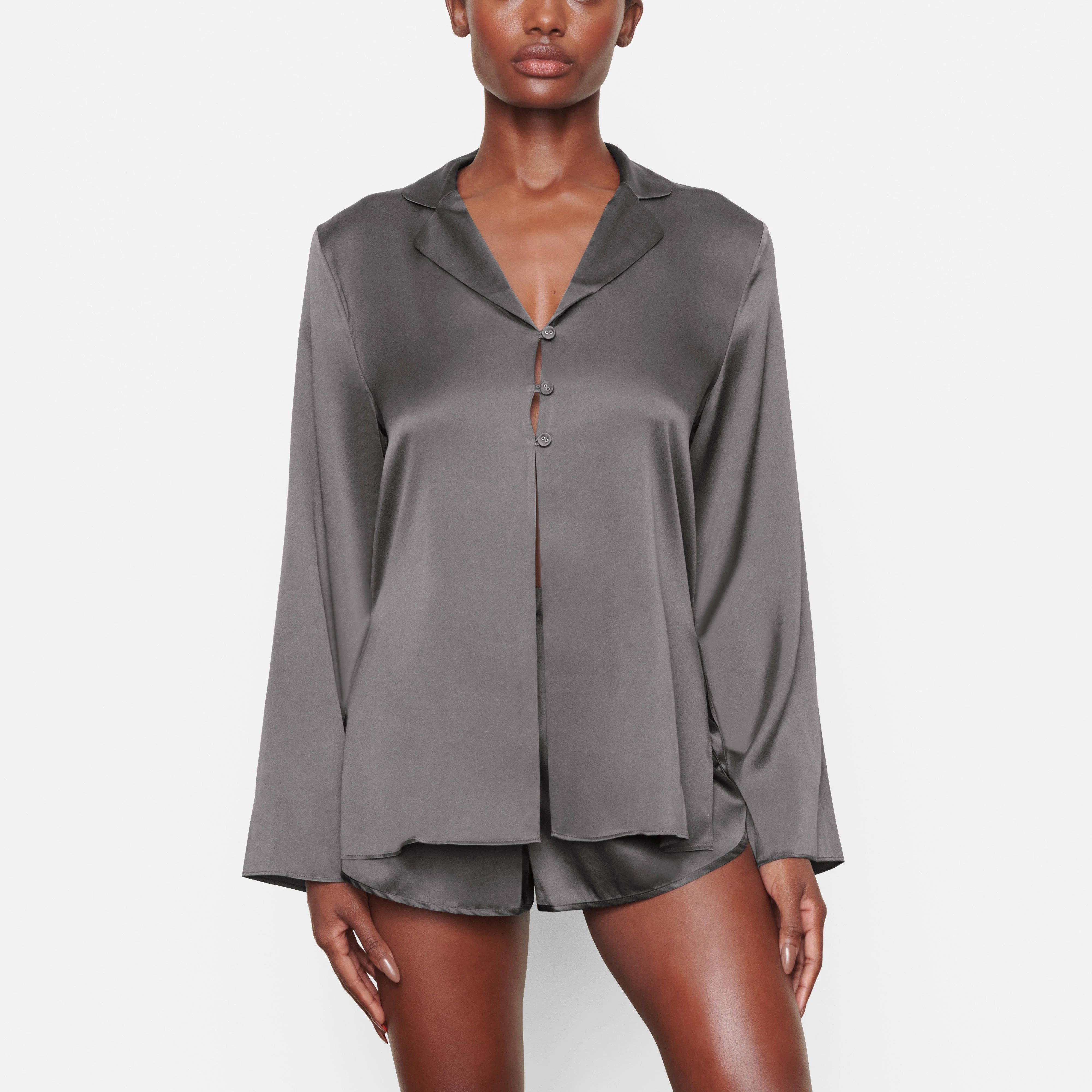 A MODEL STANDS FACING FORWARD WEARING THE SKIMS SILK OPEN NECKLINE SLEEP TOP IN GUNMETAL | SEE: XXS, XS, S
