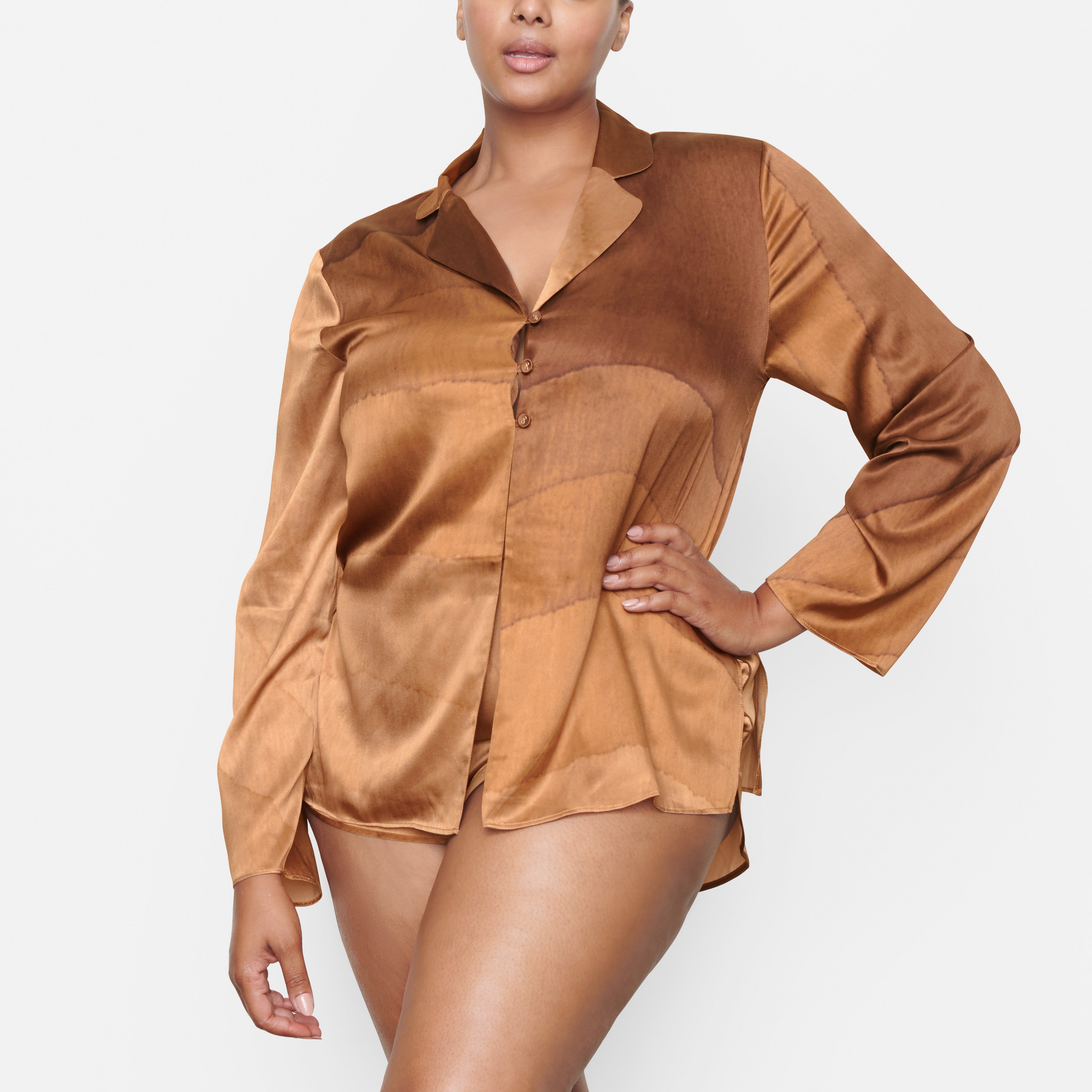 A MODEL STANDS FACING FORWARD WEARING THE SKIMS SILK OPEN NECKLINE SLEEP TOP IN OAK | SEE: 2X, 3X, 4X