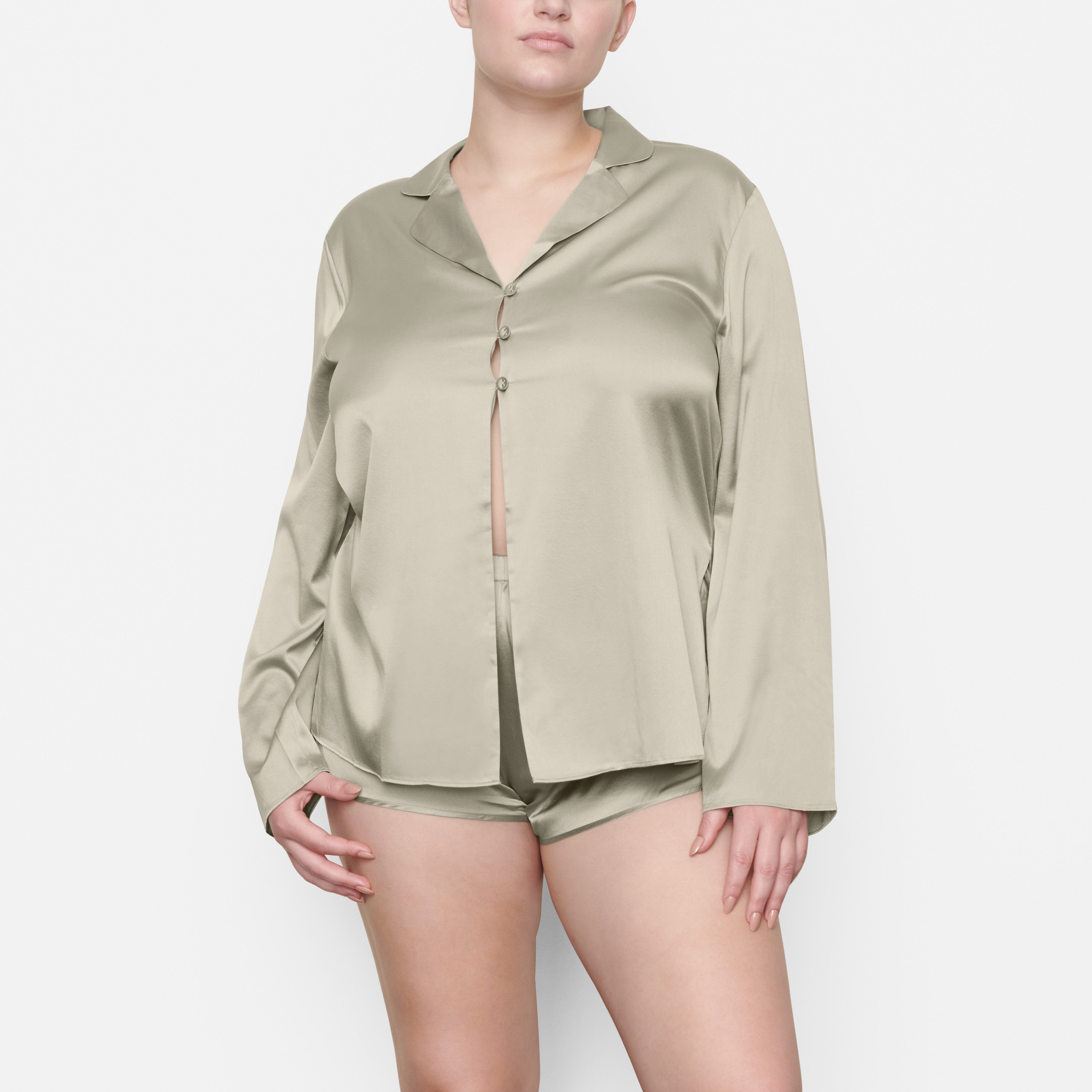 A MODEL STANDS FACING FORWARD WEARING THE SKIMS SILK OPEN NECKLINE SLEEP TOP IN TALC | SEE: M, L, XL
