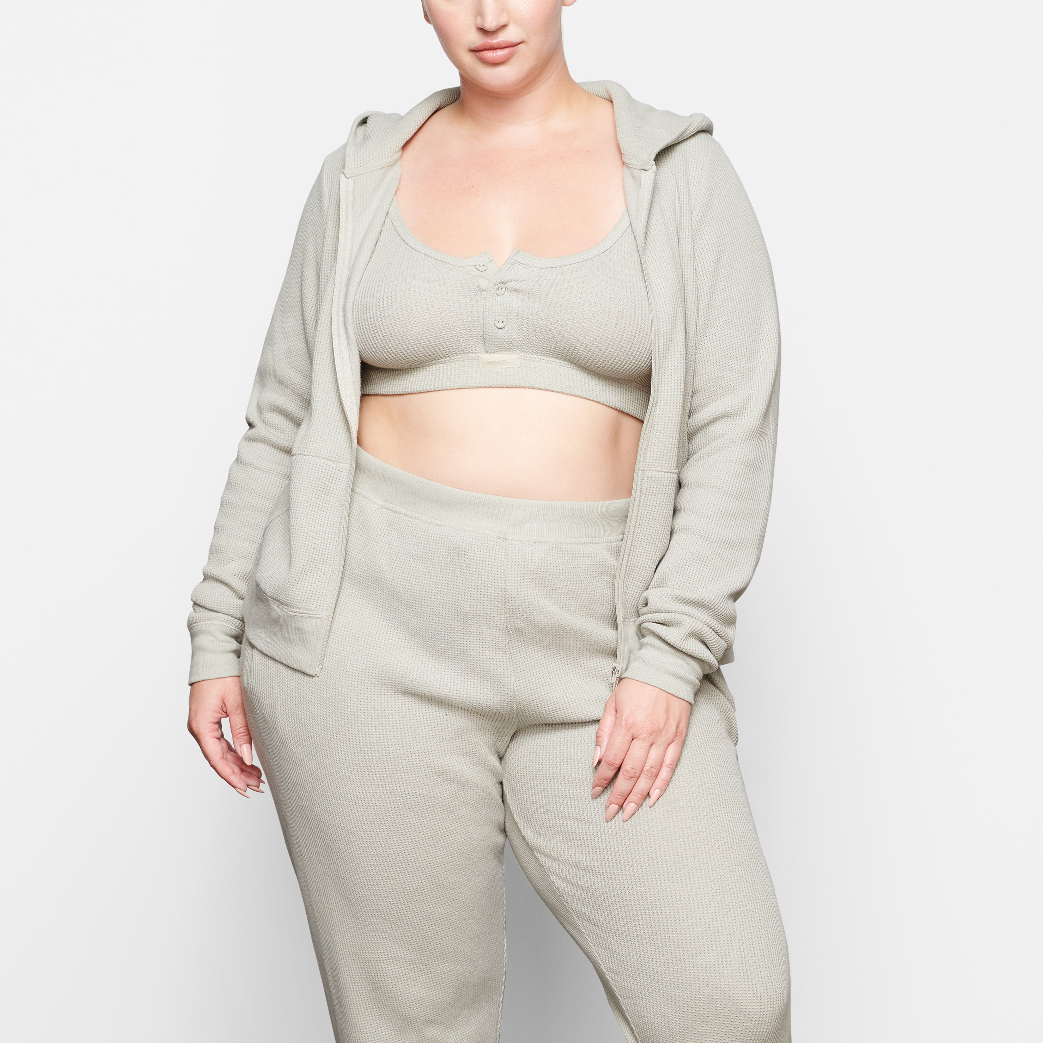 A MODEL STANDS FACING FORWARD WEARING THE SKIMS WAFFLE HOODIE IN TALC | SEE: 2X, 3X, 4X