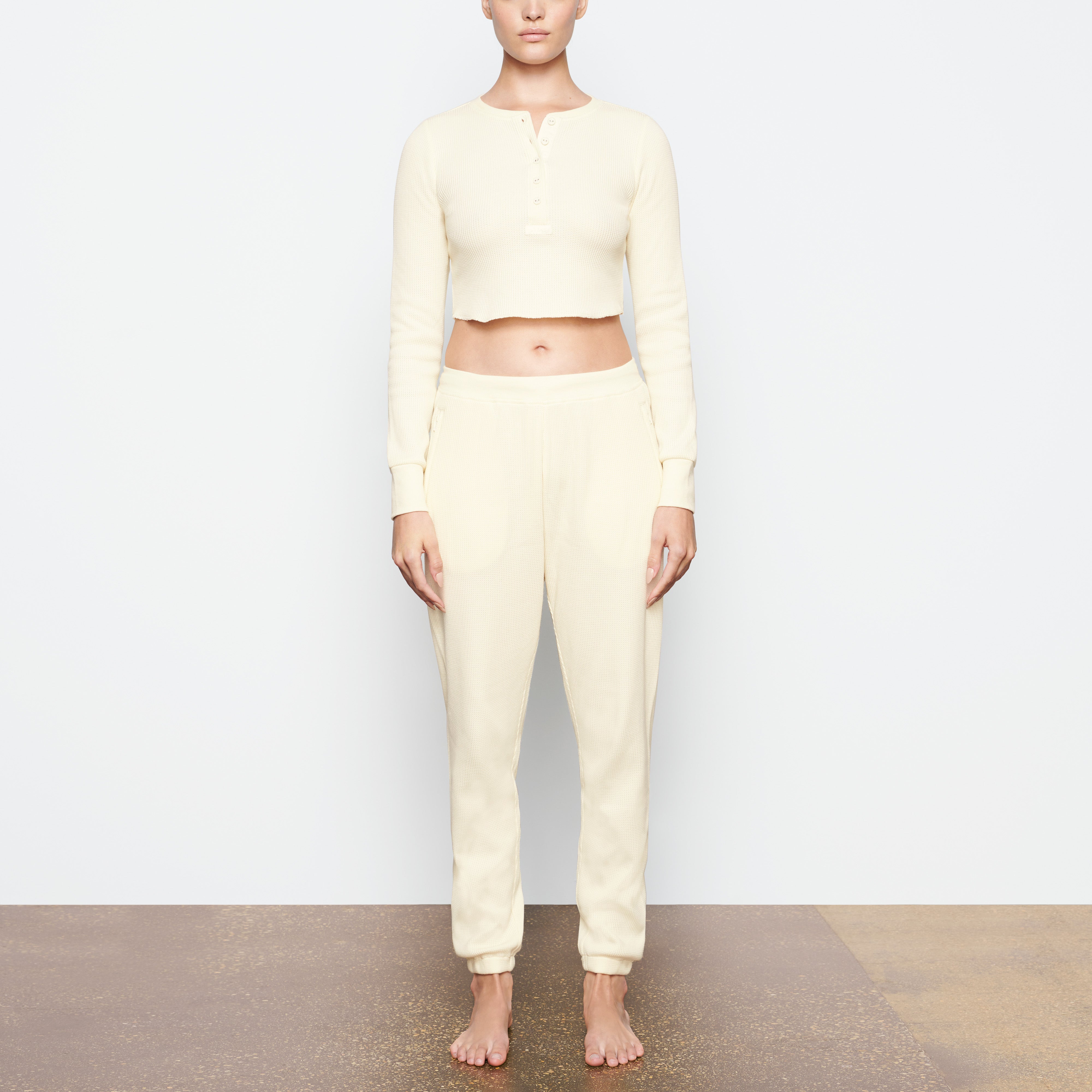A MODEL STANDS FACING FORWARD WEARING THE SKIMS WAFFLE JOGGER IN CREAM | SEE: XXS, XS, S