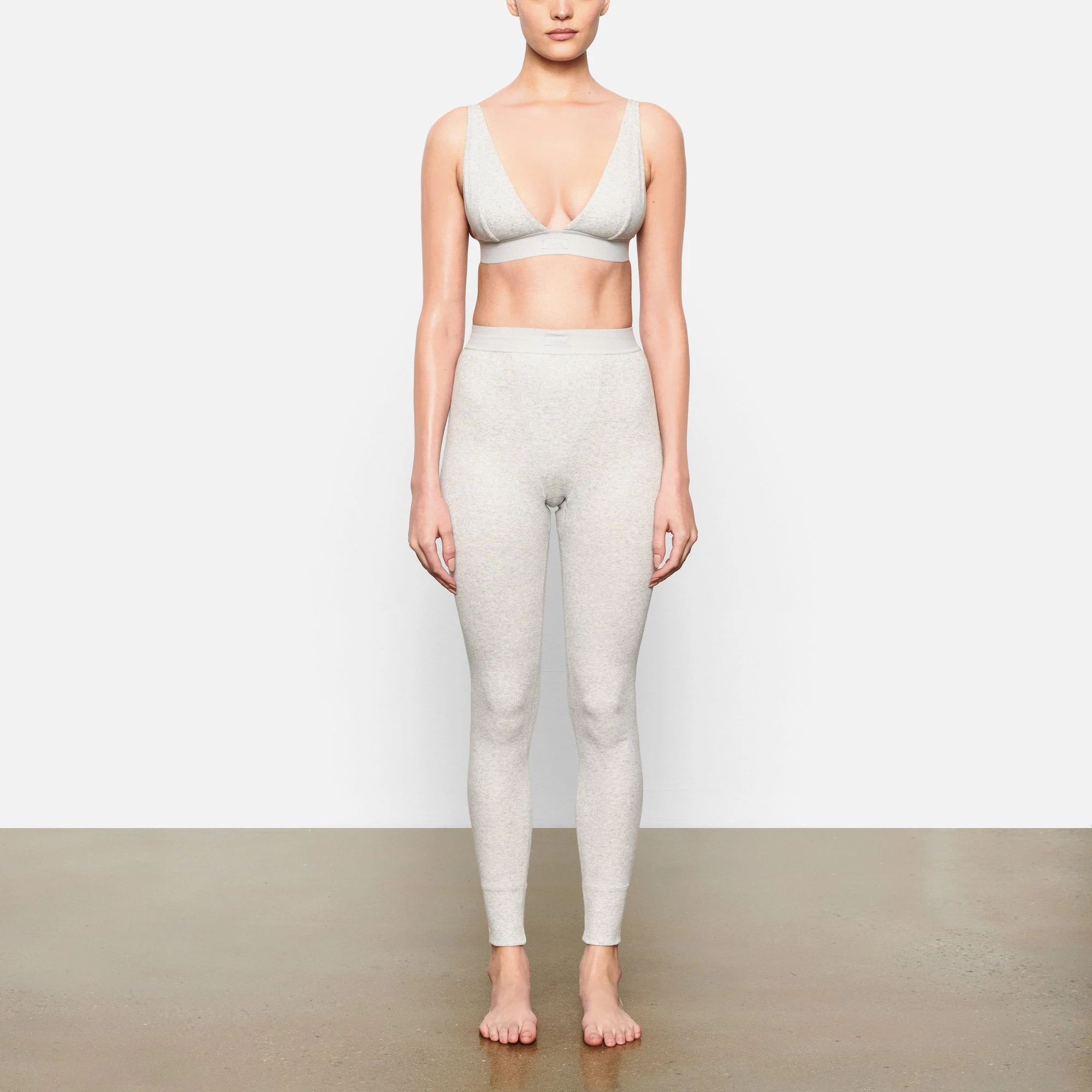 A MODEL STANDS FACING FORWARD WEARING THE COTTON RIB LEGGING | LIGHT HEATHER GREY