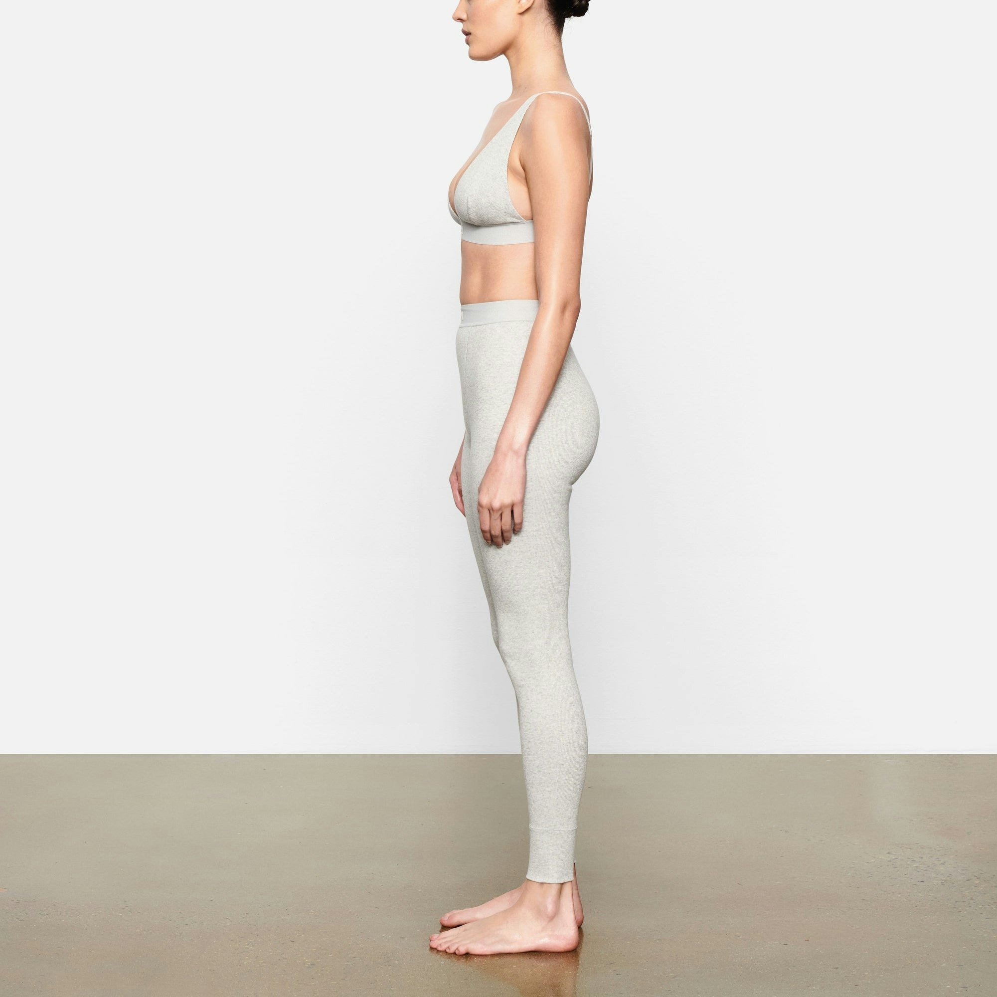 A MODEL STANDS SIDEWAYS SHOWING THE PROFILE OF THE COTTON RIB LEGGING | LIGHT HEATHER GREY