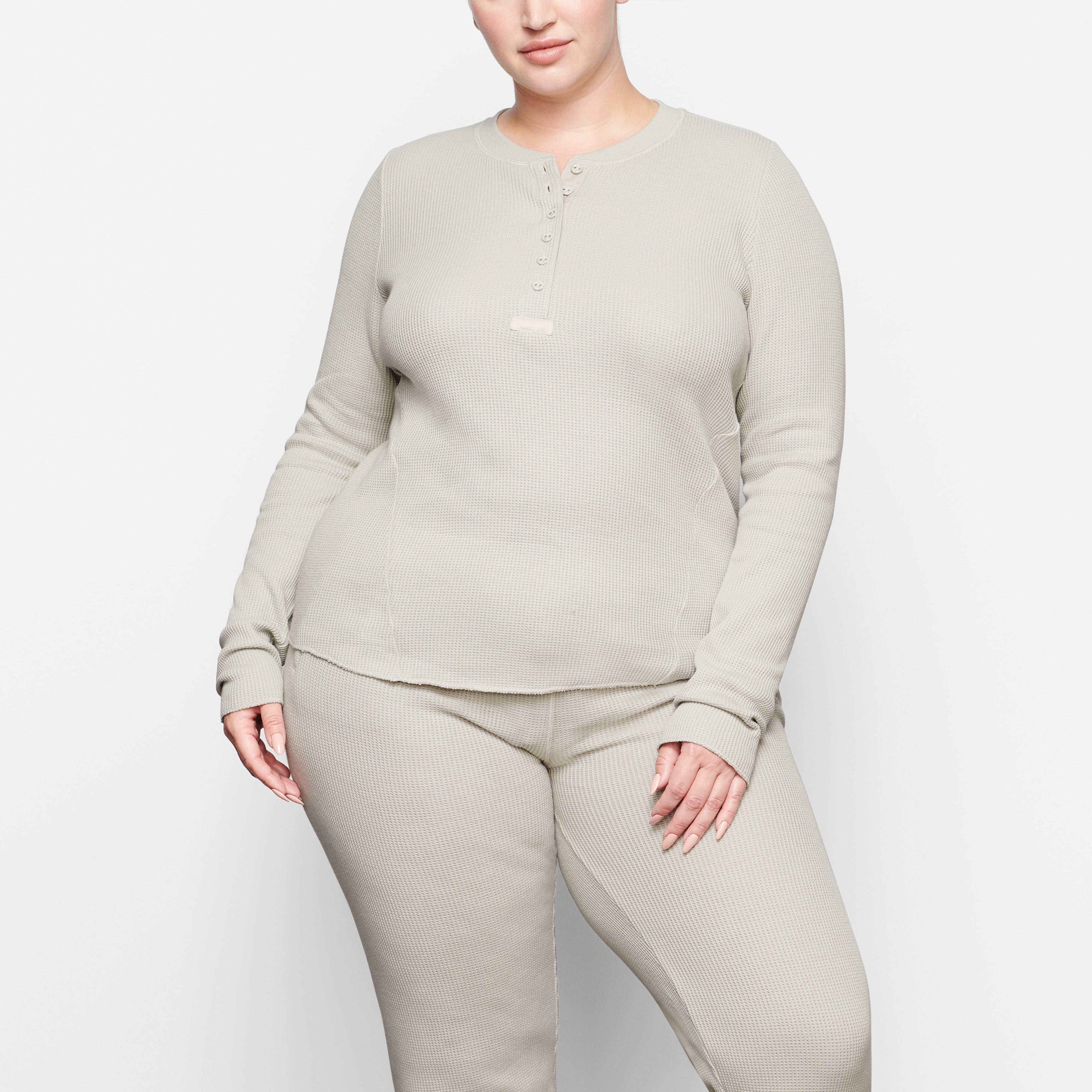 A MODEL STANDS FACING FORWARD WEARING THE SKIMS WAFFLE LONG SLEEVE HENLEY IN TALC | SEE: 2X, 3X, 4X