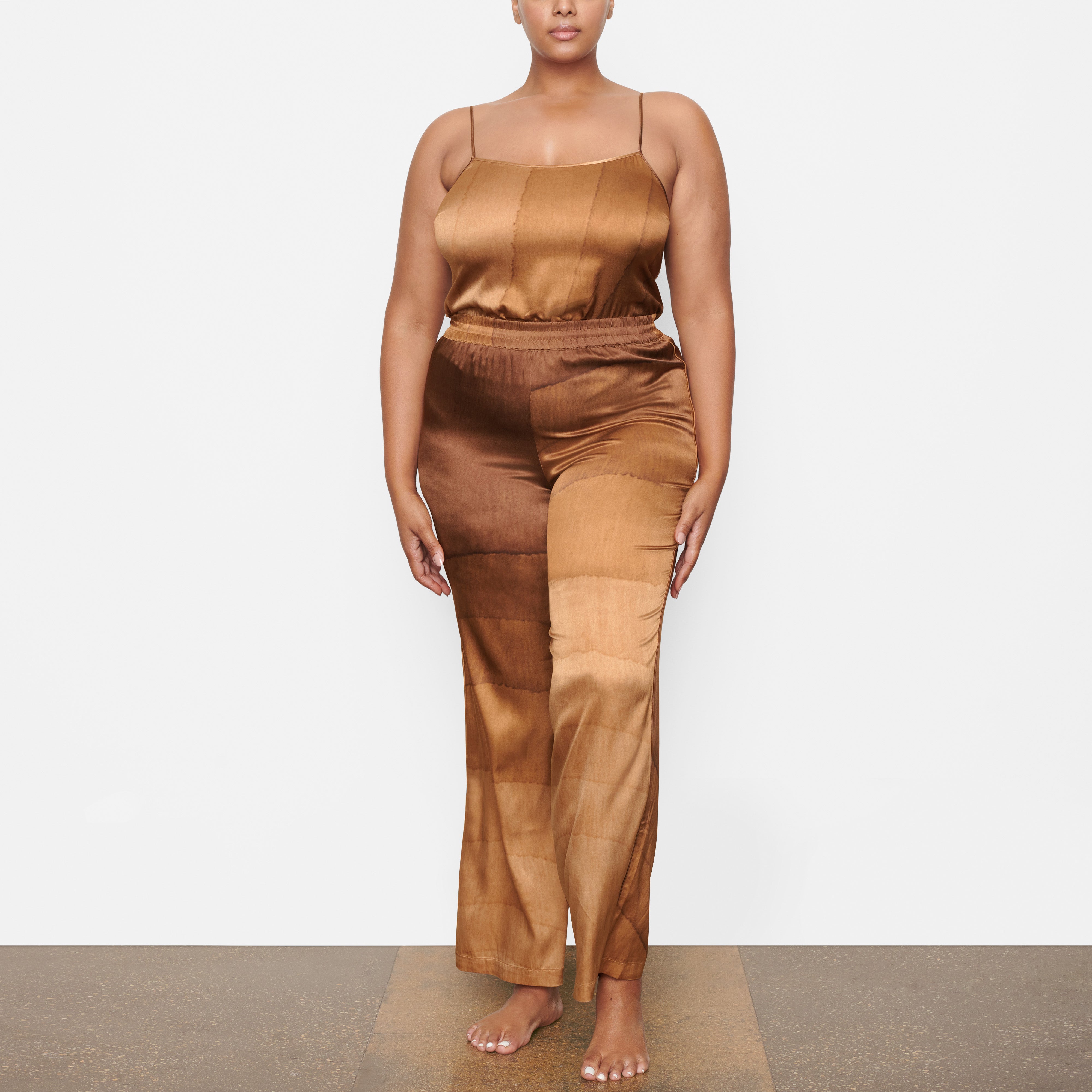 A MODEL STANDS FACING FORWARD WEARING THE SKIMS SILK WIDE LEG SLEEP PANT IN OAK | SEE: 2X, 3X, 4X