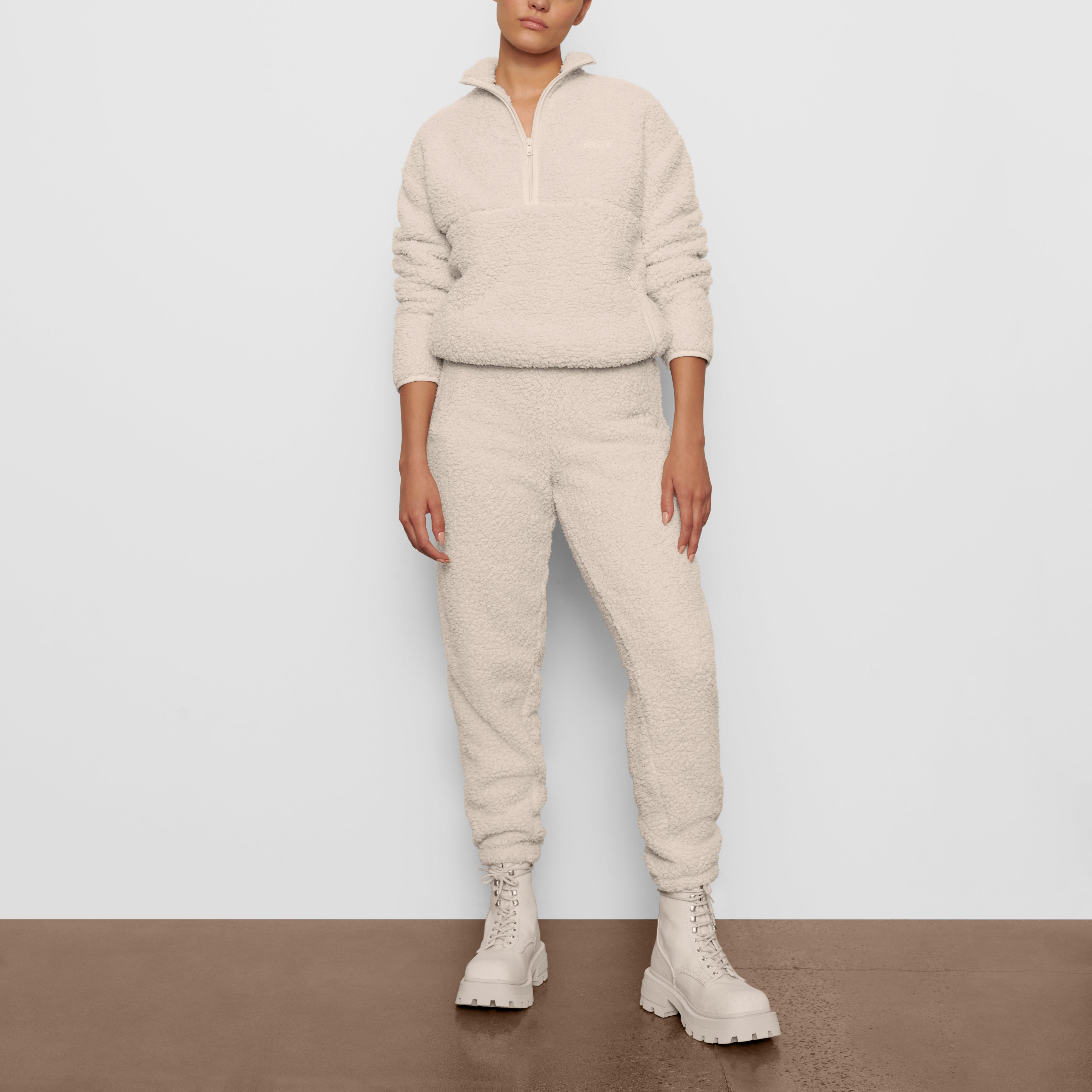 A MODEL STANDS FACING FORWARD WEARING THE SKIMS TEDDY PULLOVER IN BONE | SEE: XXS, XS, S