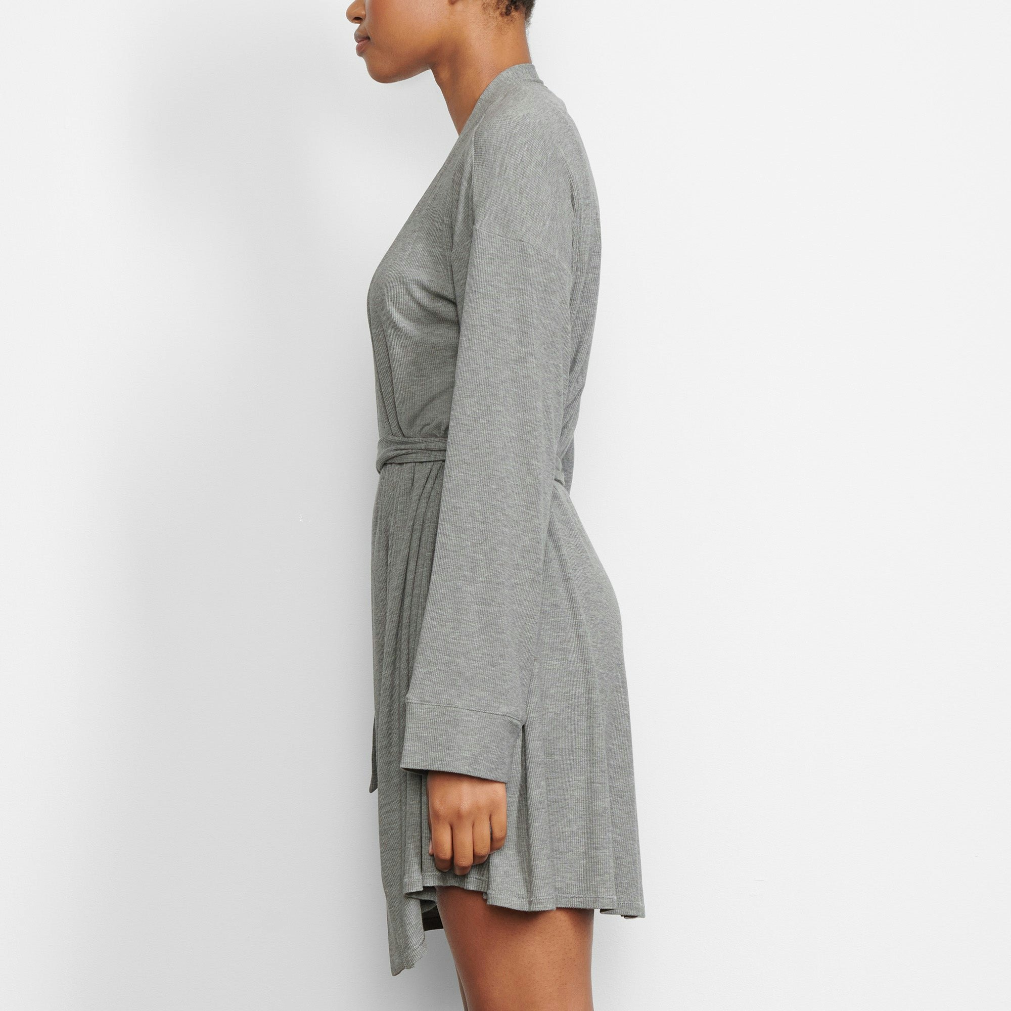 A MODEL STANDS FACING FORWARD WEARING THE SKIMS SOFT LOUNGE ROBE IN HEATHER GREY