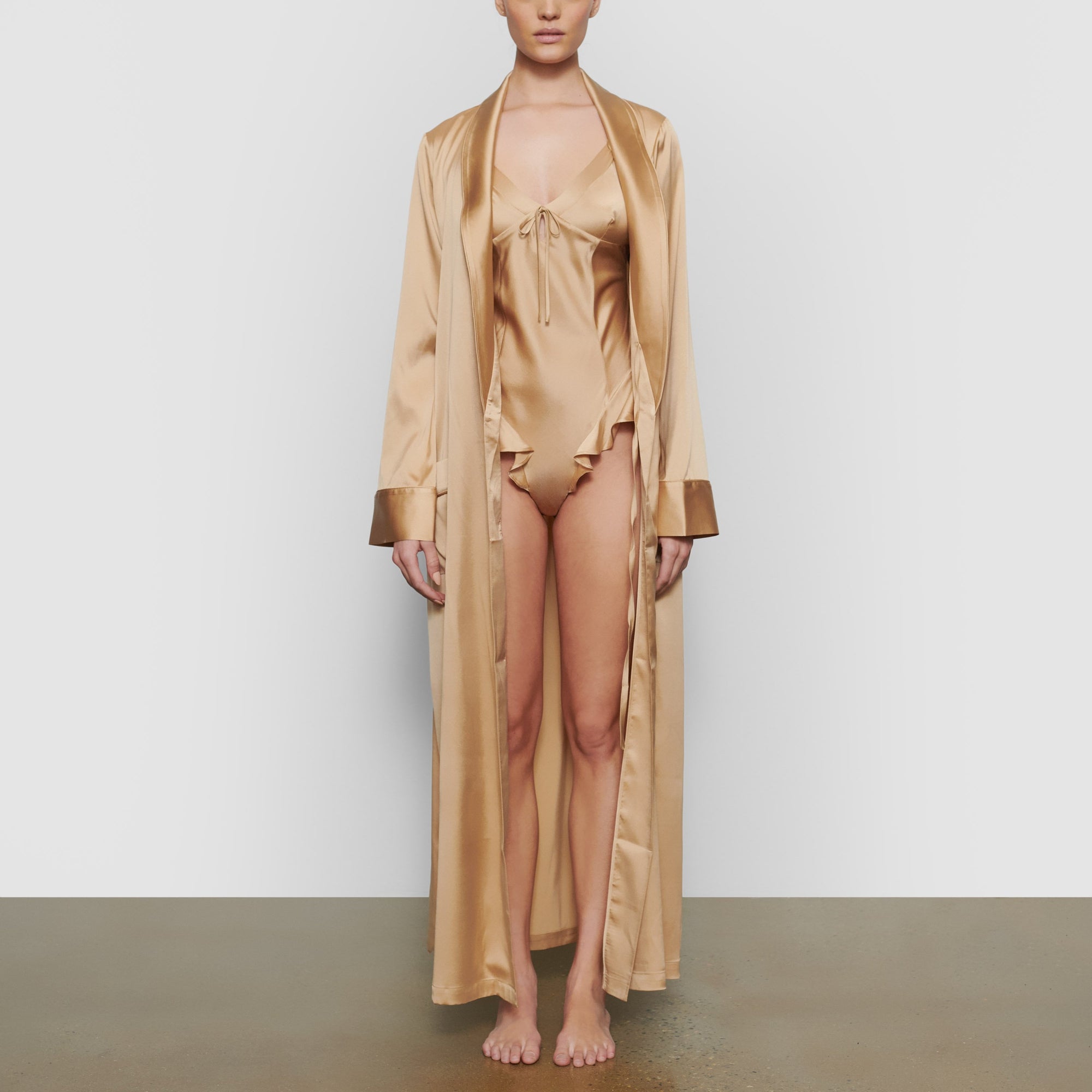 A MODEL STANDS FACING FORWARD WEARING THE SKIMS SILK SLEEP ROBE IN HONEY | SEE: XXS, XS, S