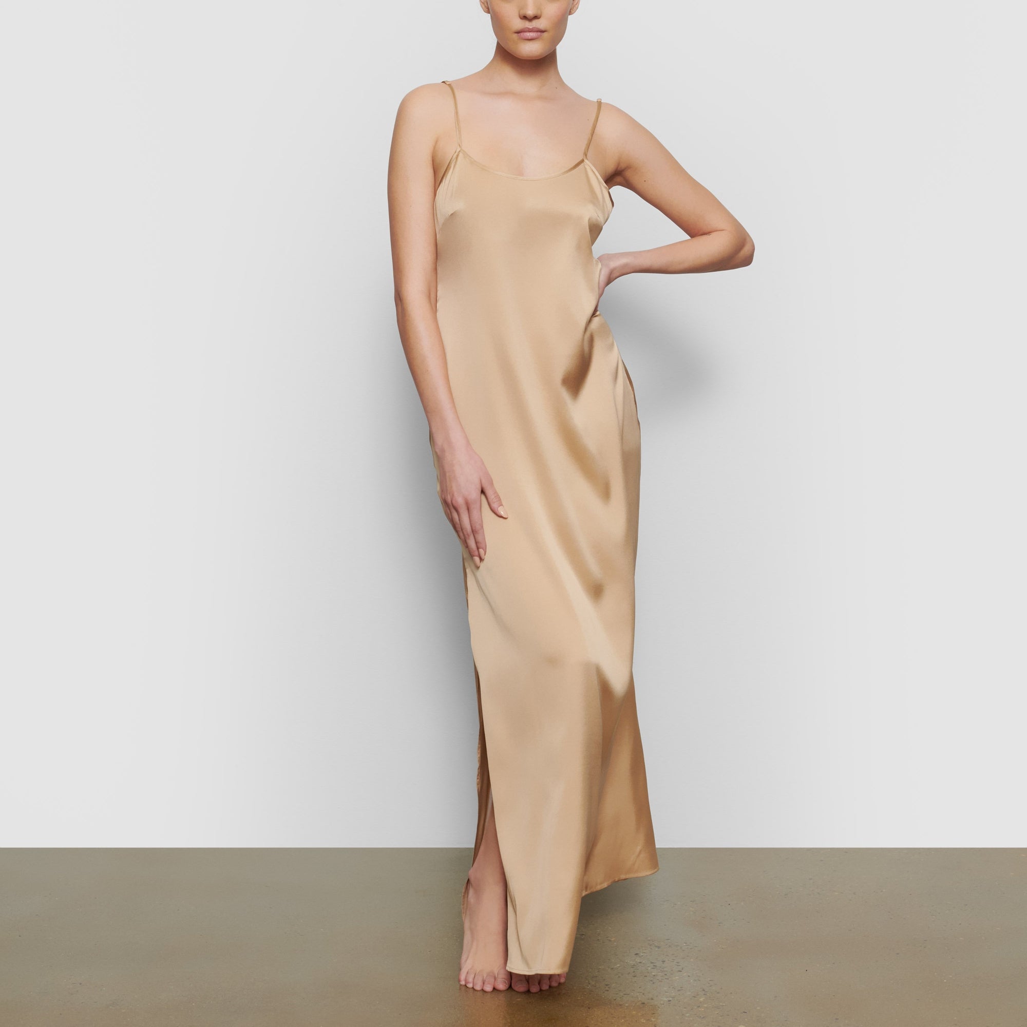 A MODEL STANDS FACING FORWARD WEARING THE SKIMS SILK LONG SLEEP SLIP IN HONEY | SEE: XXS, XS, S
