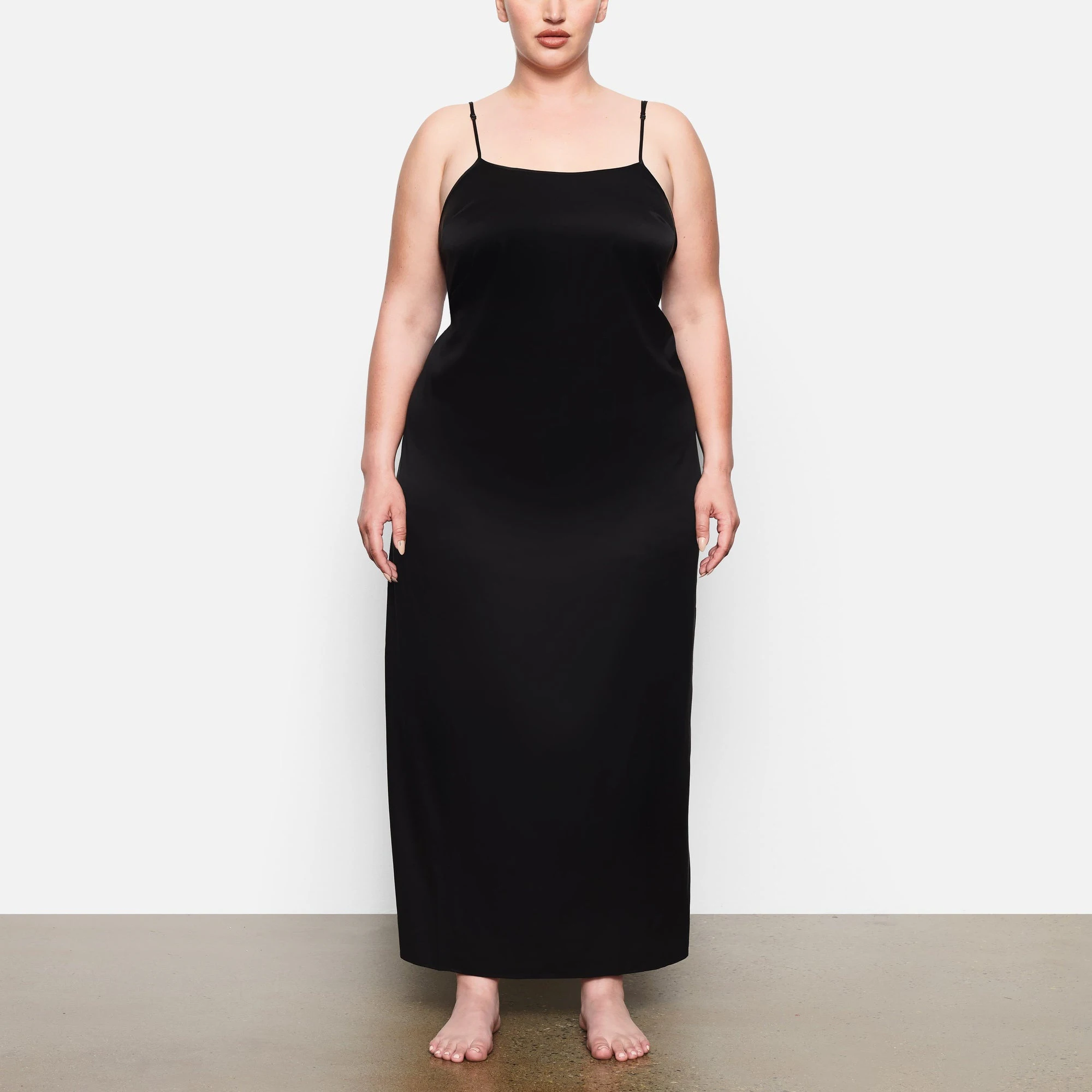 A MODEL STANDS FACING FORWARD WEARING THE SKIMS SILK LONG SLEEP SLIP IN SOOT | SEE: 2X, 3X, 4X